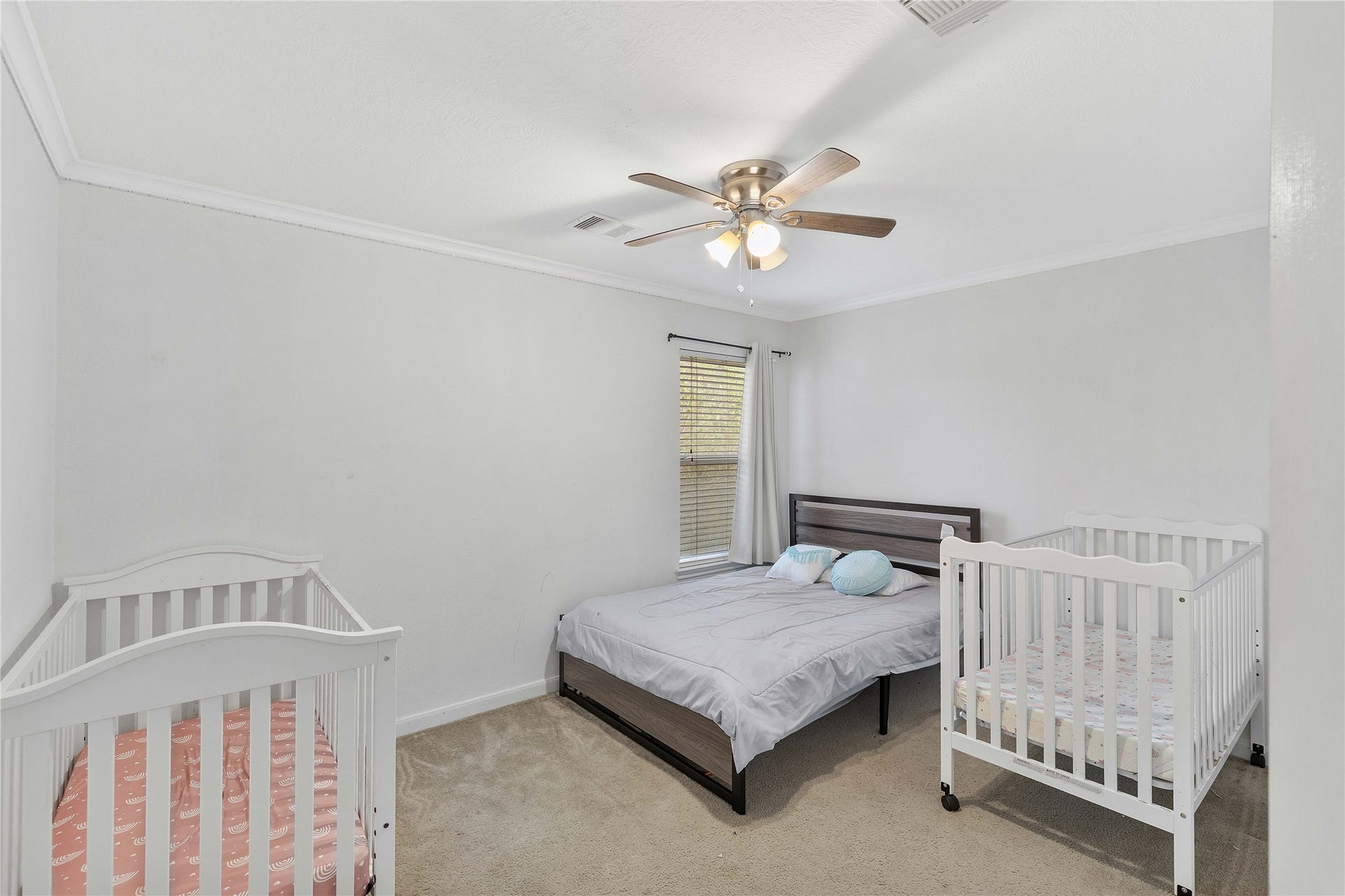 2910 Ribbon Creek Way, Spring, TX 77389 Charming bedroom with a cozy layout, featuring a comfortable bed, two cribs, and a ceiling fan, all bathed in natural light from a large window.