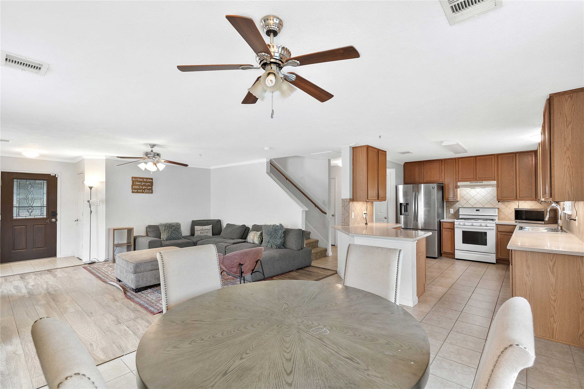 2910 Ribbon Creek Way, Spring, TX 77389 Spacious open-concept living area with modern kitchen featuring stainless steel appliances and ample cabinetry. Cozy living room with plush sectional and ceiling fan for comfort.