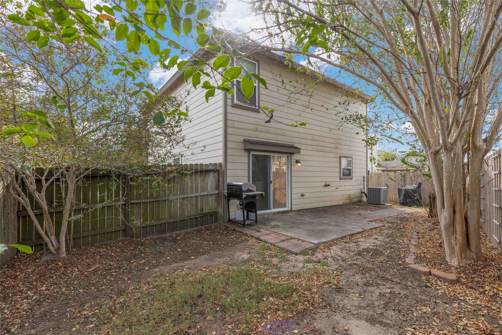 2910 Ribbon Creek Way, Spring, TX 77389 Charming backyard features a cozy patio area perfect for outdoor grilling and entertaining, surrounded by mature trees and a privacy fence for a serene setting.