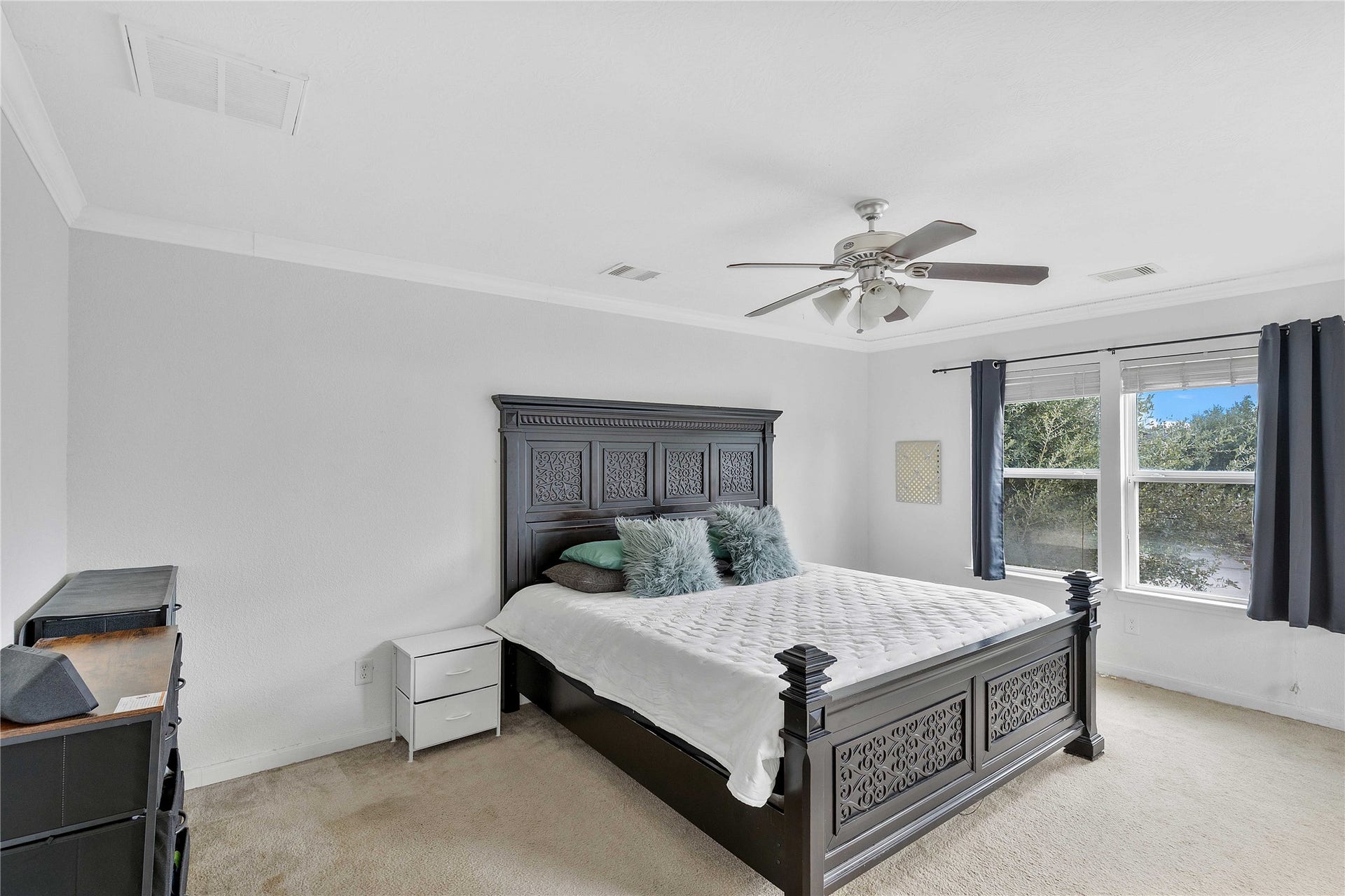 2910 Ribbon Creek Way, Spring, TX 77389 Spacious bedroom featuring a large window for natural light, elegant dark wood furniture, and a ceiling fan for comfort.