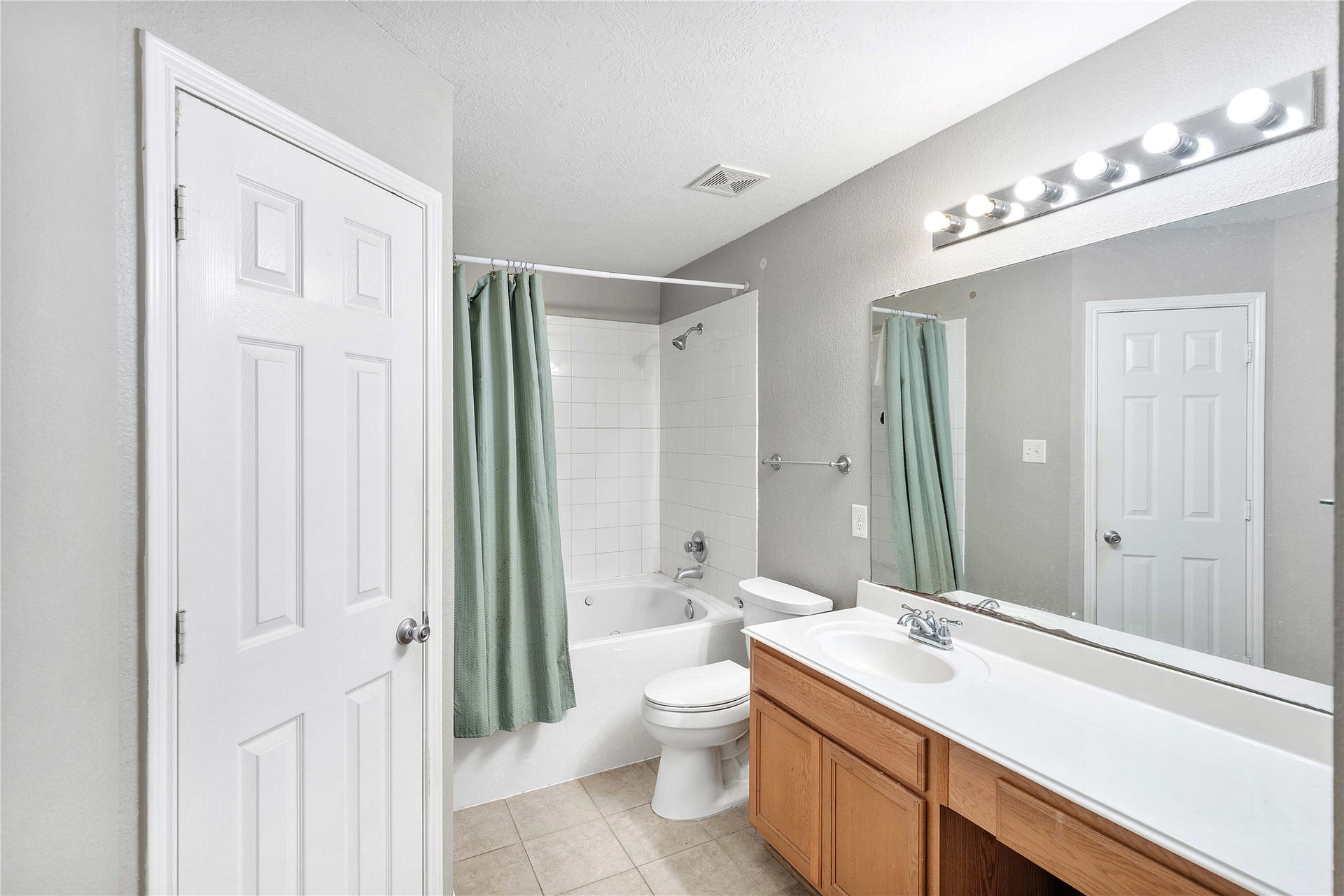 2910 Ribbon Creek Way, Spring, TX 77389 Bright and inviting bathroom featuring a spacious vanity with ample storage, a full bathtub with a shower, and modern lighting for a refreshing ambiance.