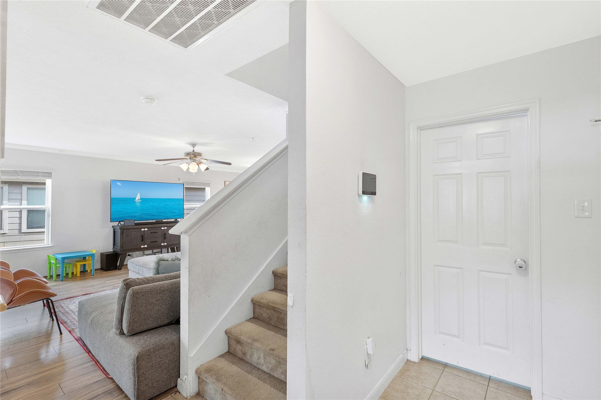 2910 Ribbon Creek Way, Spring, TX 77389 Inviting entryway leads into a cozy living room with abundant natural light, featuring a ceiling fan and stylish wood flooring, perfect for family relaxation.
