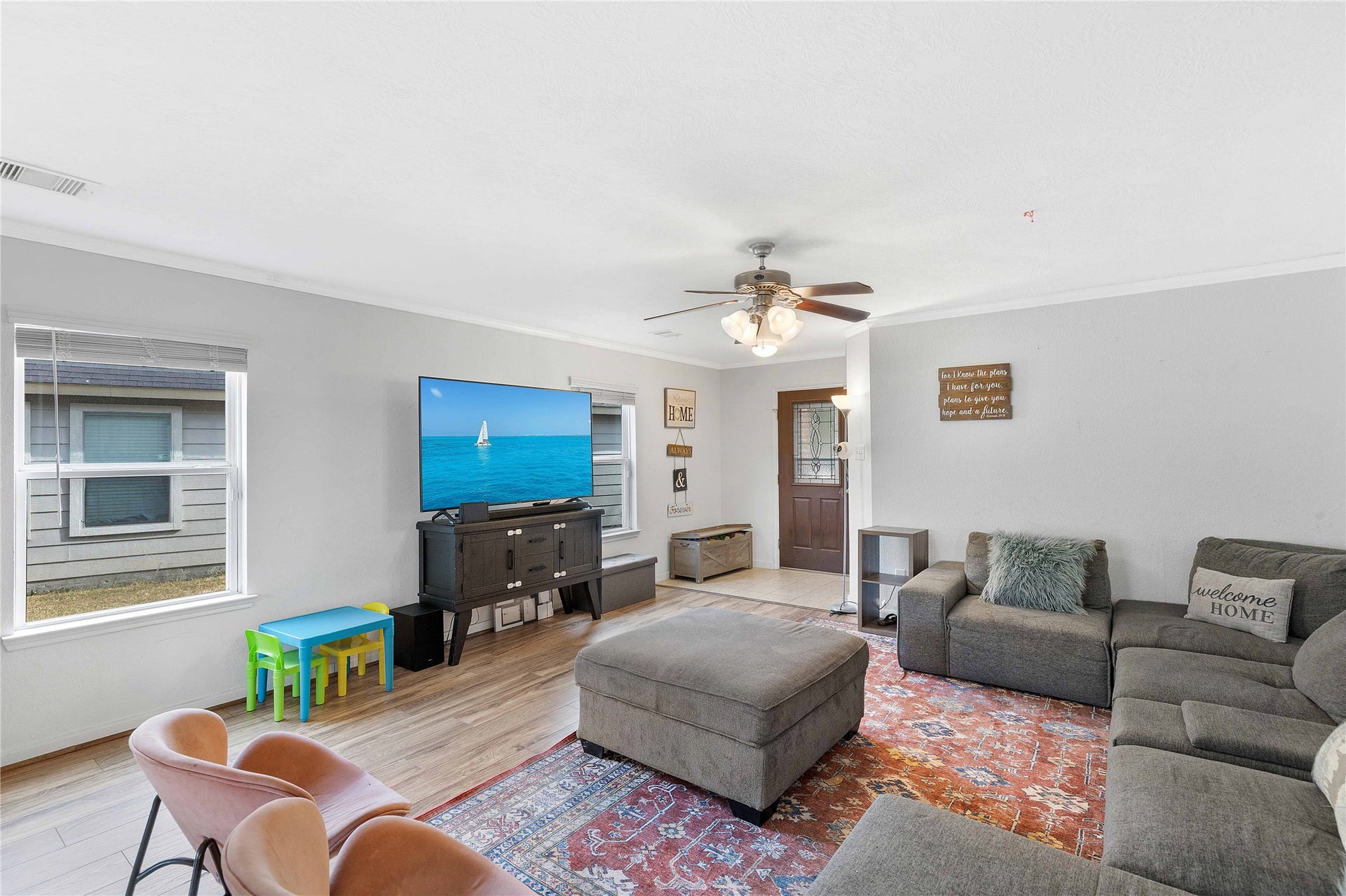 2910 Ribbon Creek Way, Spring, TX 77389 Spacious living room with abundant natural light, featuring a cozy sectional sofa, stylish ceiling fan, and inviting decor.