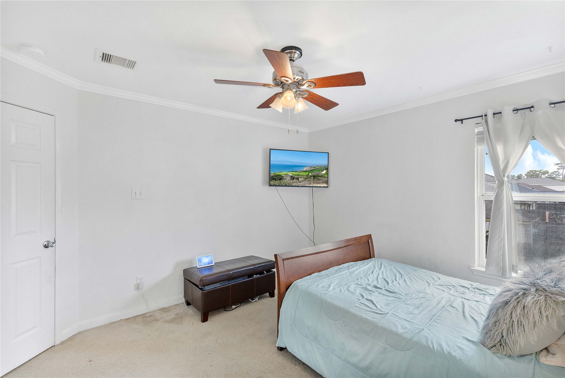 2910 Ribbon Creek Way, Spring, TX 77389 Bright and inviting bedroom featuring a ceiling fan, ample natural light from the window, and a mounted TV, creating a cozy and functional space.