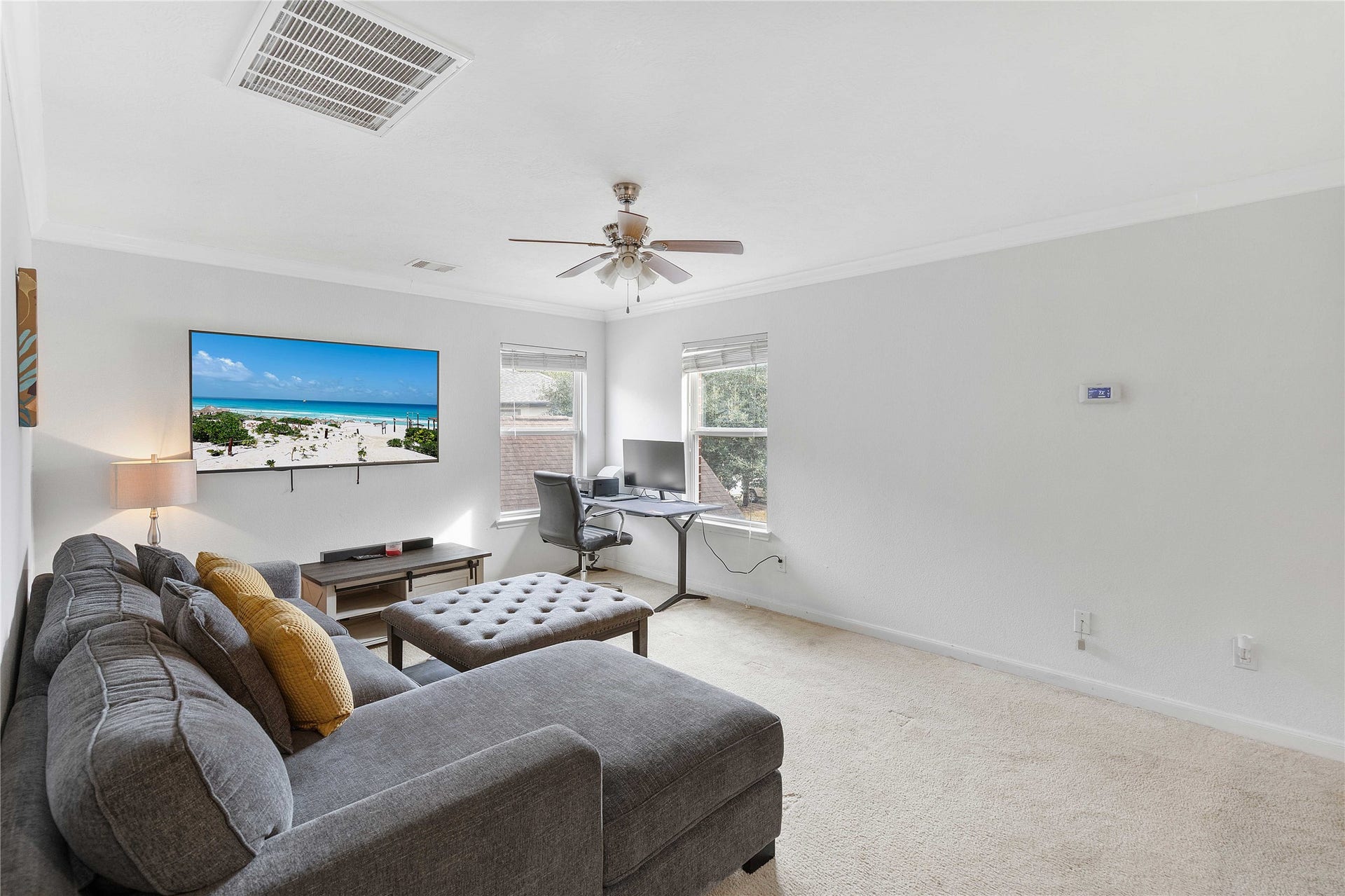 2910 Ribbon Creek Way, Spring, TX 77389 Spacious and bright living area with a cozy sectional sofa, wall-mounted TV, and a convenient corner office desk, perfect for relaxation and productivity.