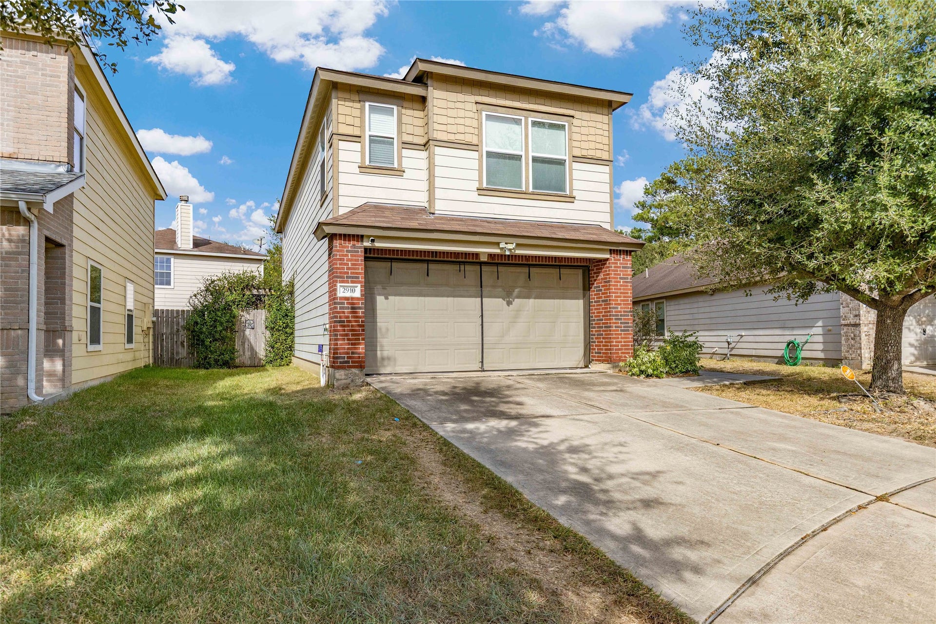 2910 Ribbon Creek Way, Spring, TX 77389 Charming two-story home with a brick and siding exterior, featuring a spacious driveway and attached garage, surrounded by a well-maintained lawn and mature trees.