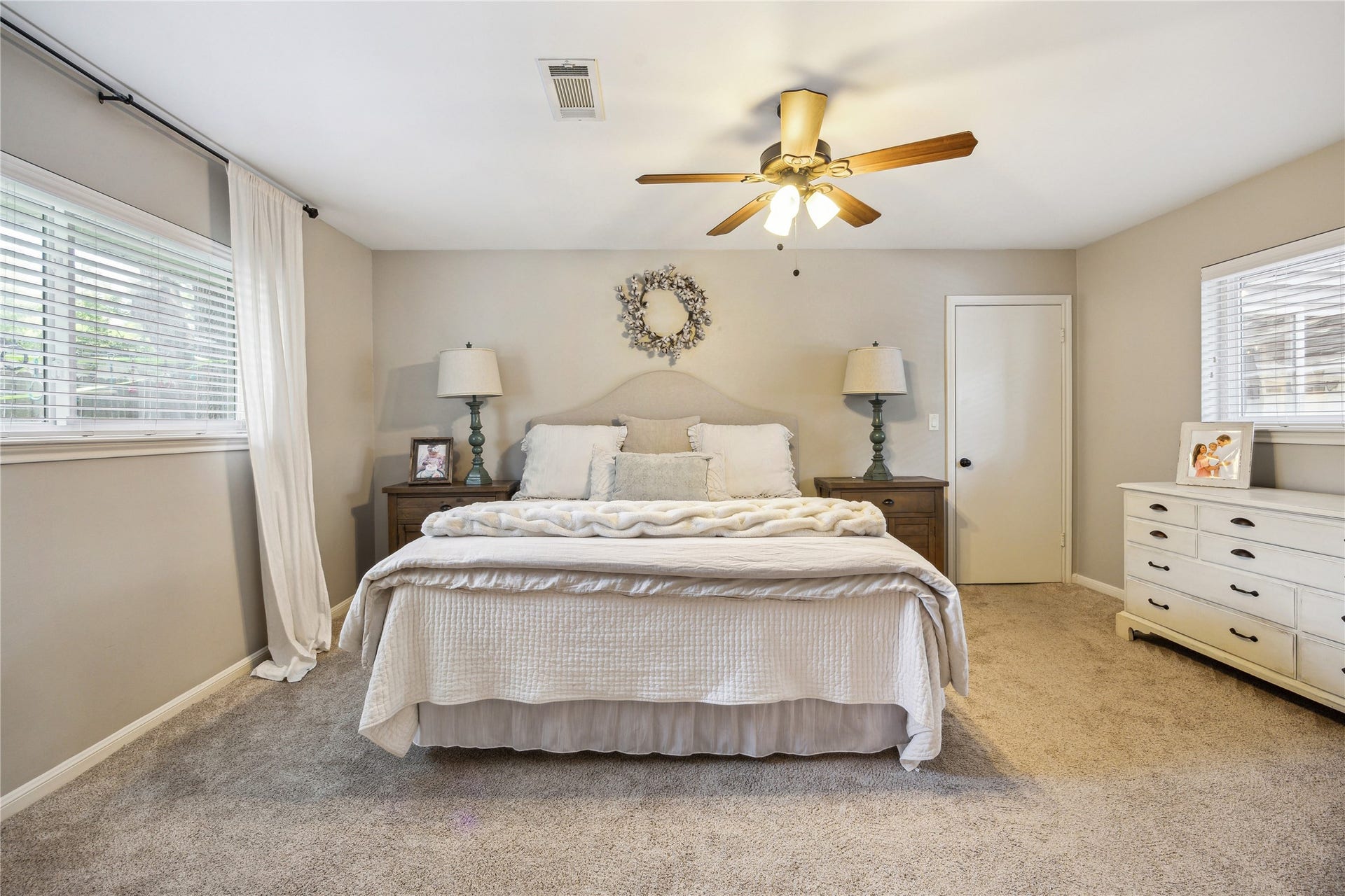 10714 Piping Rock Lane, Houston, TX 77042 Windows on two walls bring natural light into the primary bedroom, featuring neutral finishes, carpeting and a ceiling fan.