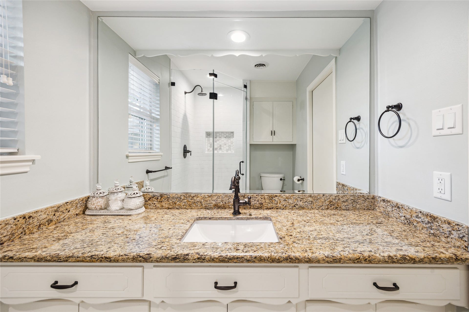 10714 Piping Rock Lane, Houston, TX 77042 An expansive granite countertop, white cabinetry and a large mirror provide ample space for daily routines.