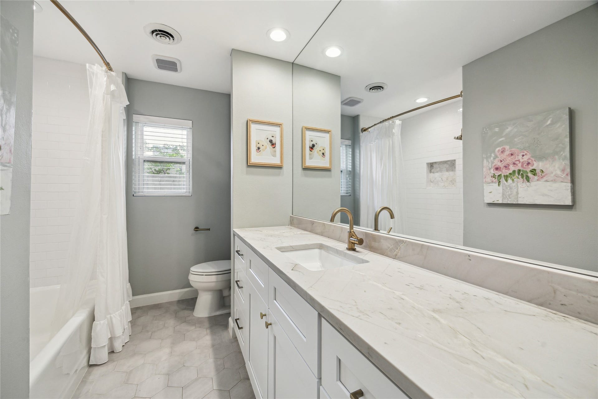 10714 Piping Rock Lane, Houston, TX 77042 A long vanity with ample storage, a large mirror and hexagonal floor tile highlight this bathroom.