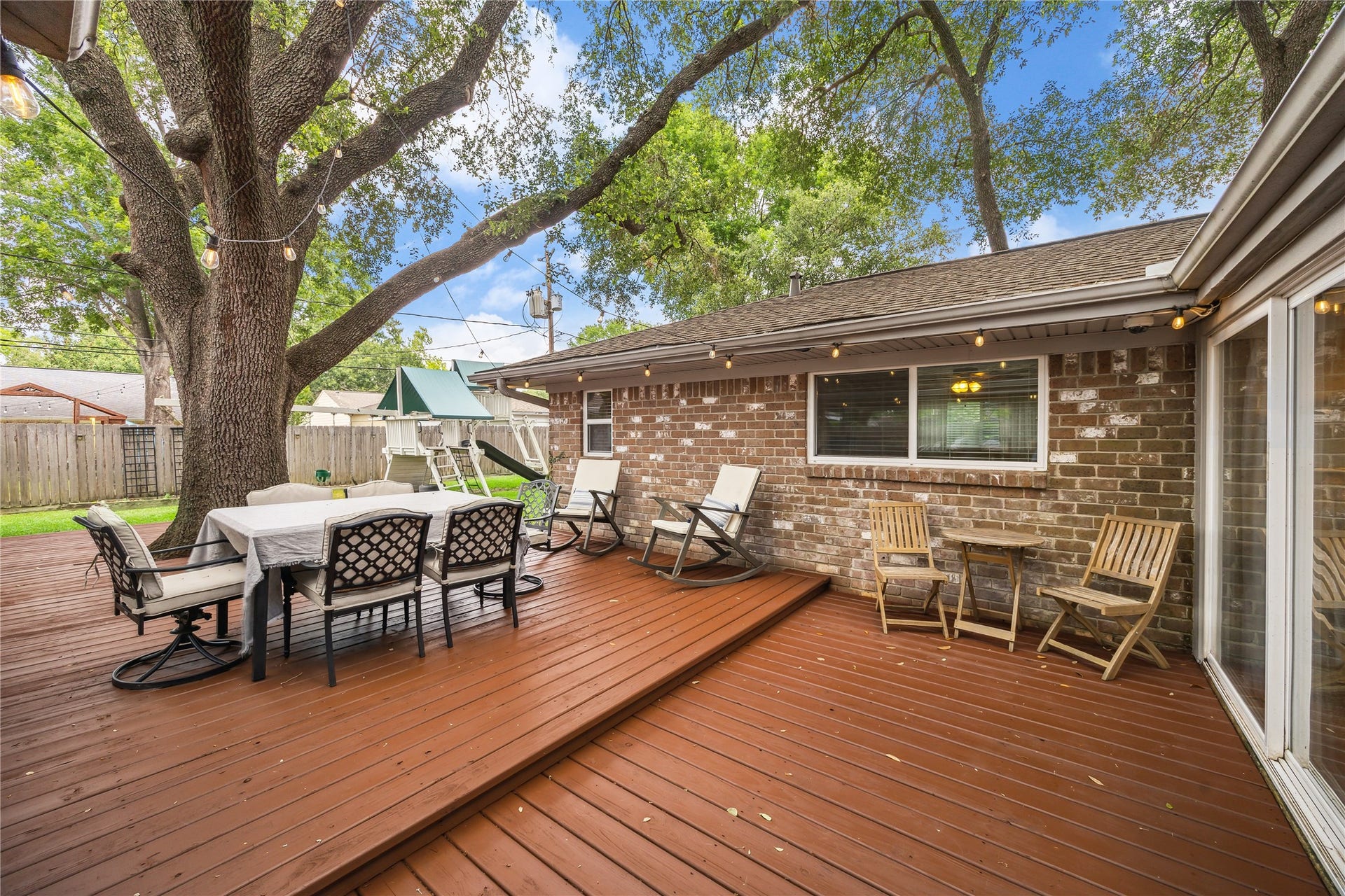 10714 Piping Rock Lane, Houston, TX 77042 A tiered wood deck offers distinct spaces for outdoor dining and relaxing beneath a mature shade tree.