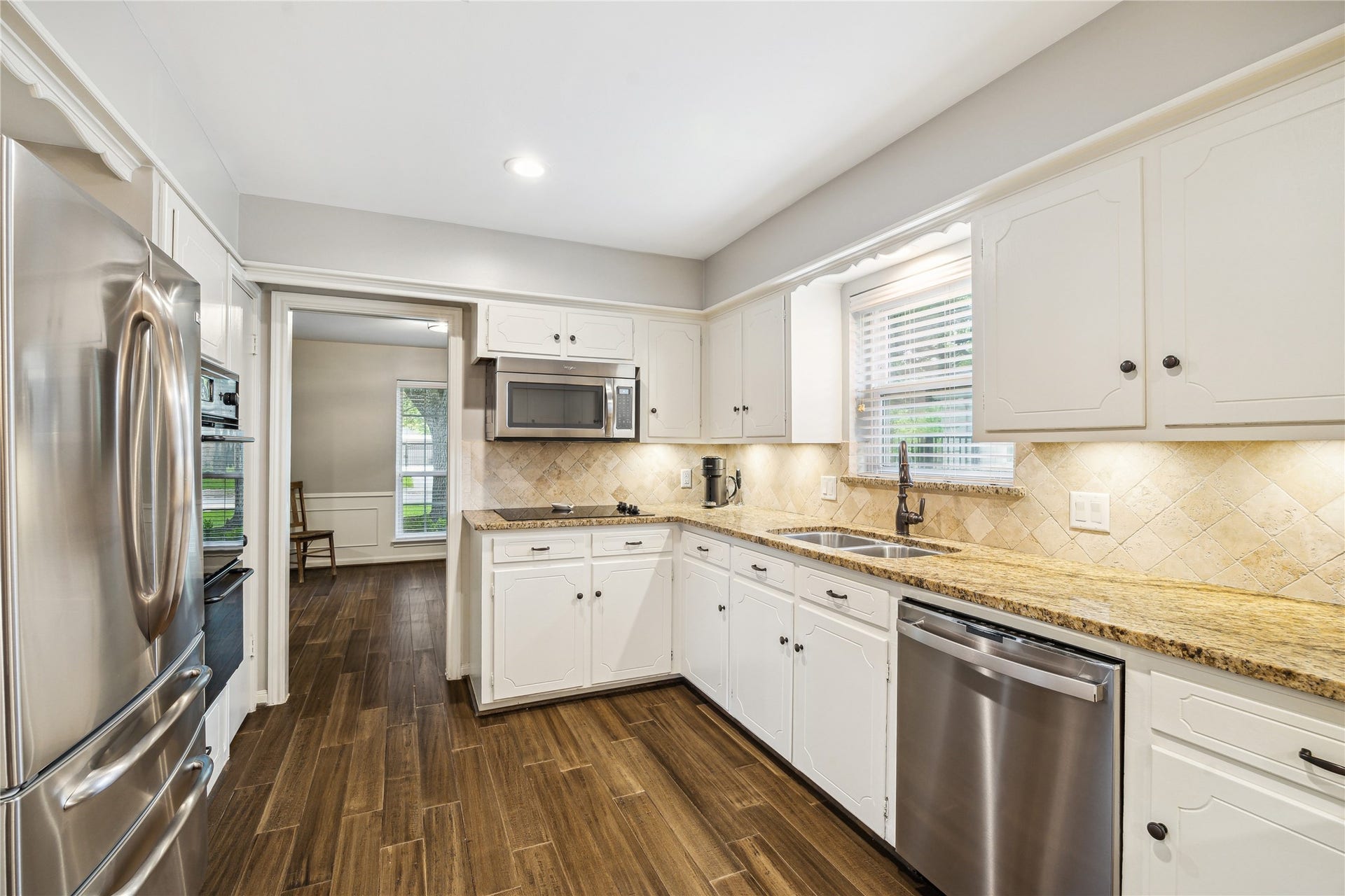 10714 Piping Rock Lane, Houston, TX 77042 White cabinetry, granite countertops and stainless steel appliances line the kitchen, with a window above the sink.
