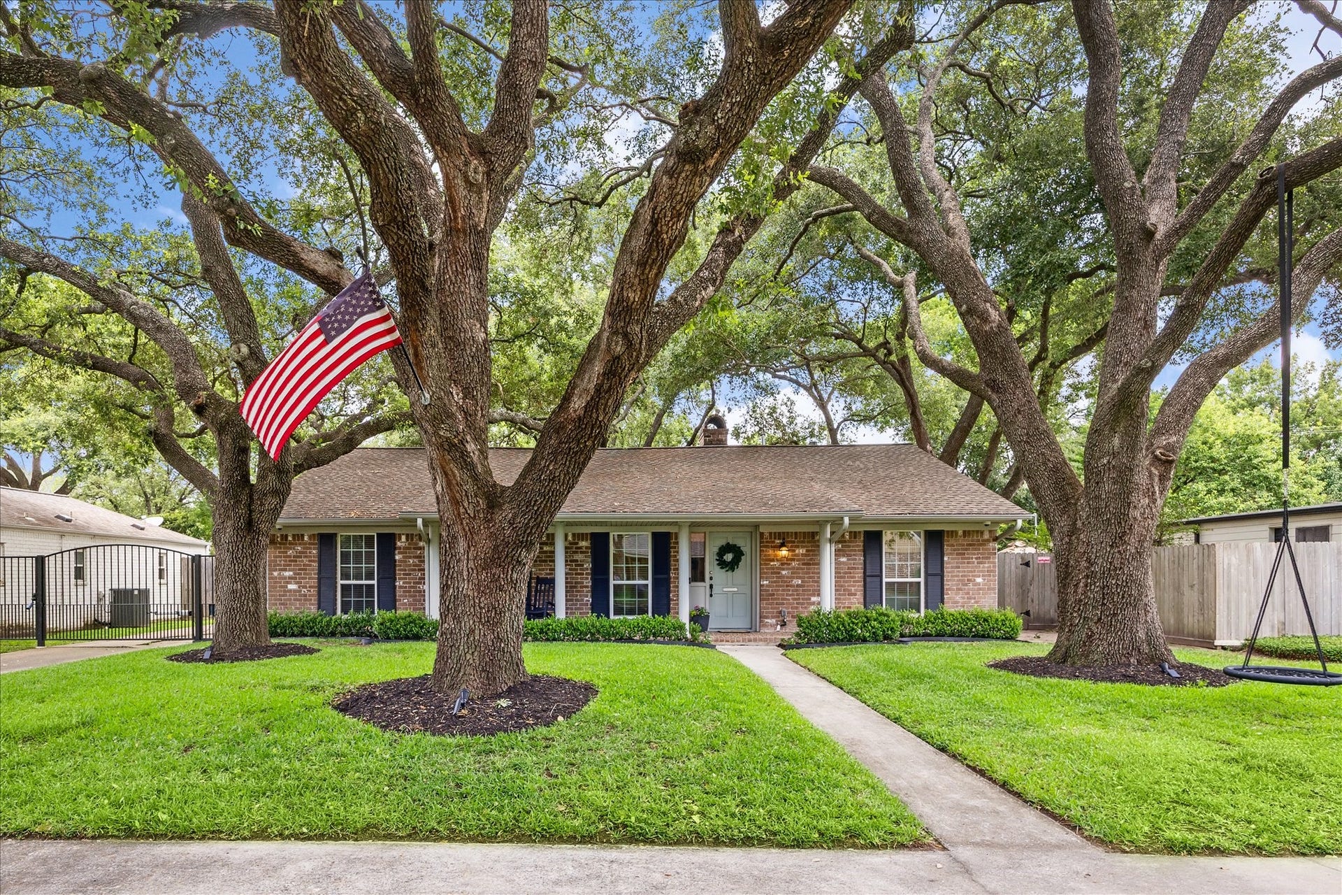 10714 Piping Rock Lane, Houston, TX 77042 Mature trees frame this single-story brick home, with a spacious front lawn and a walkway leading to the covered porch.