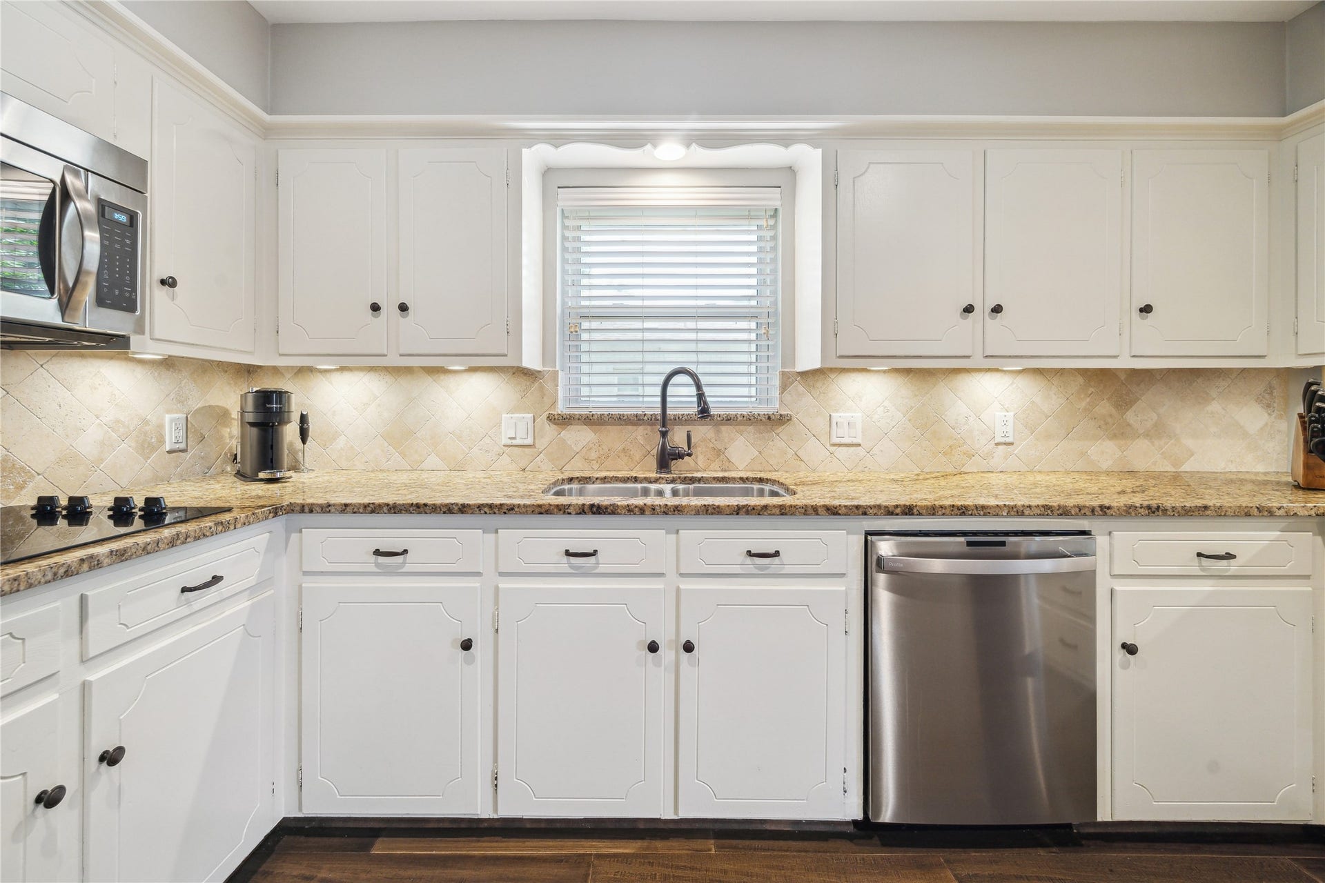 10714 Piping Rock Lane, Houston, TX 77042 A window above the sink adds natural light, with under-cabinet lighting illuminating the granite countertops and tile backsplash.