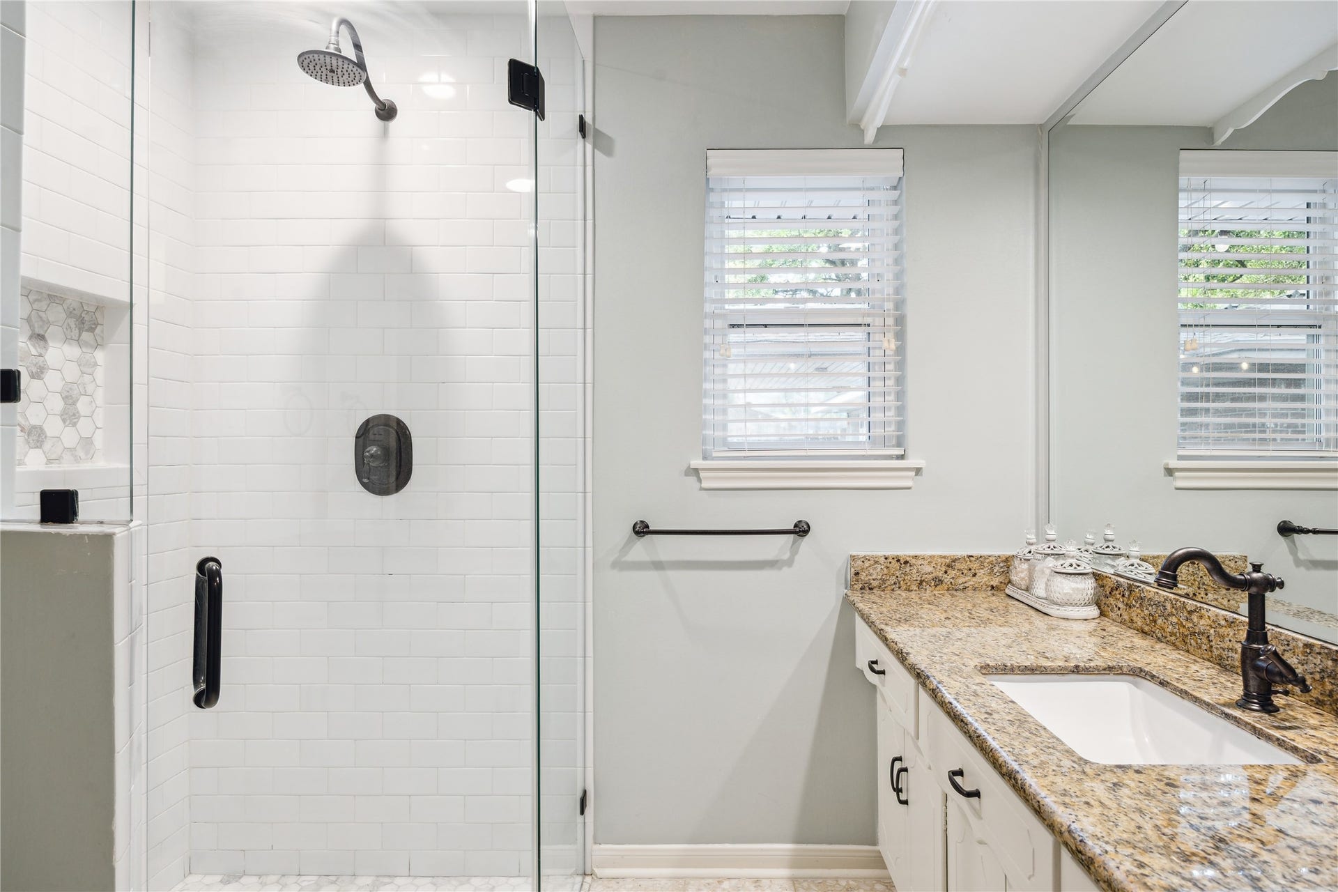 10714 Piping Rock Lane, Houston, TX 77042 A glass-enclosed shower with white tile and dark fixtures sits beside a granite-topped vanity.