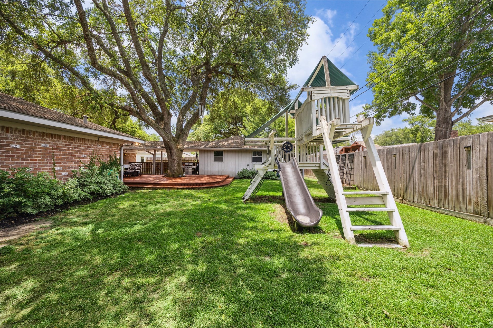 10714 Piping Rock Lane, Houston, TX 77042 A fenced lawn, mature trees and a play structure complement the deck, providing multiple ways to enjoy the outdoor space.