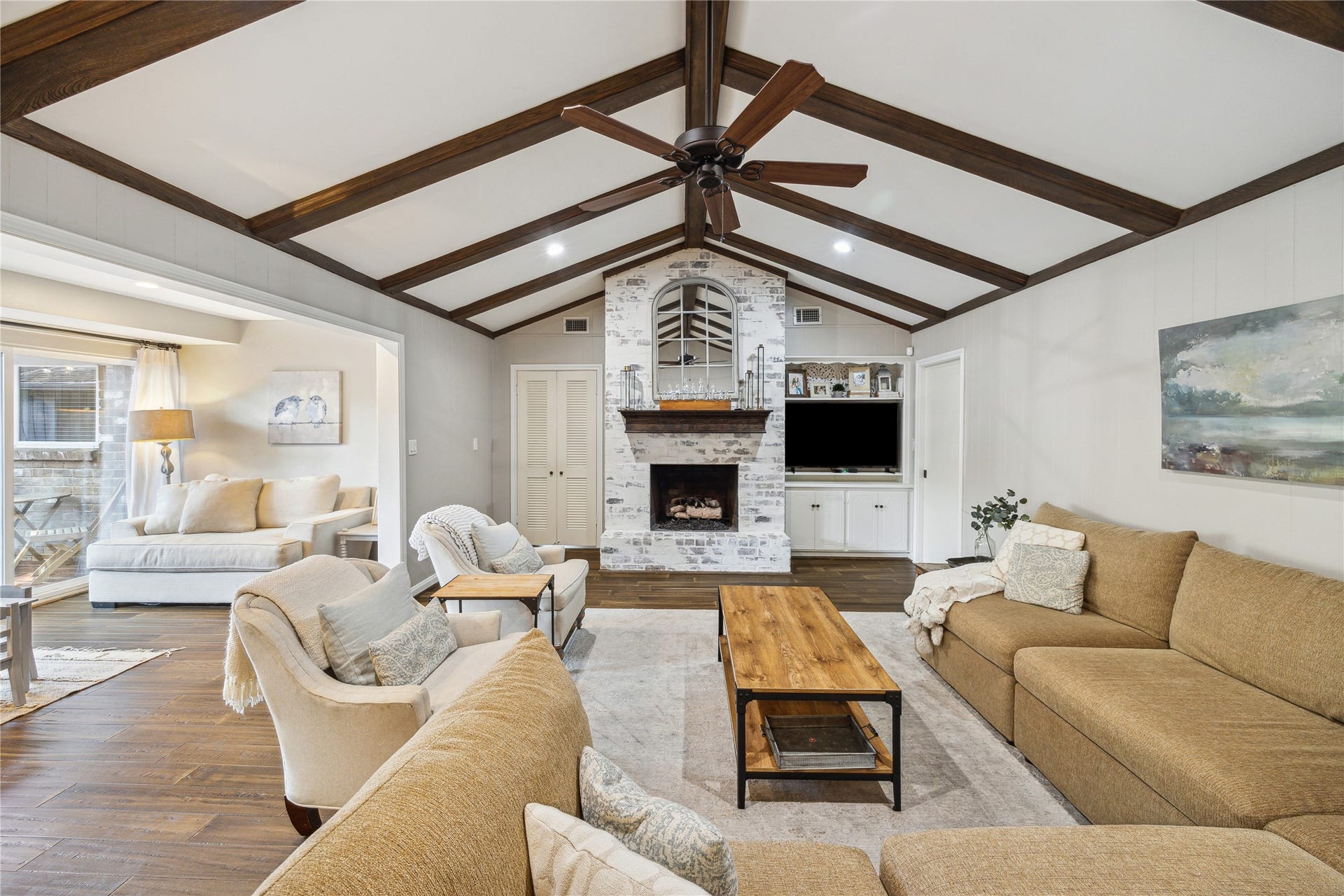 10714 Piping Rock Lane, Houston, TX 77042 A vaulted ceiling with exposed wood beams highlights the living room, centered around a painted brick fireplace and built-in cabinetry.