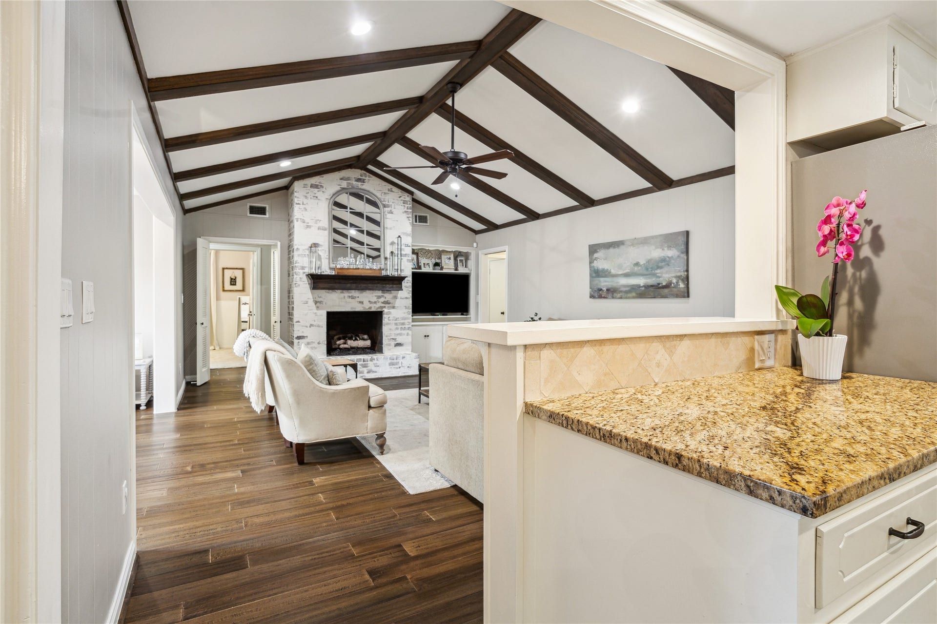 10714 Piping Rock Lane, Houston, TX 77042 A granite breakfast bar connects the kitchen to the living room, keeping the fireplace and beamed ceiling in view.
