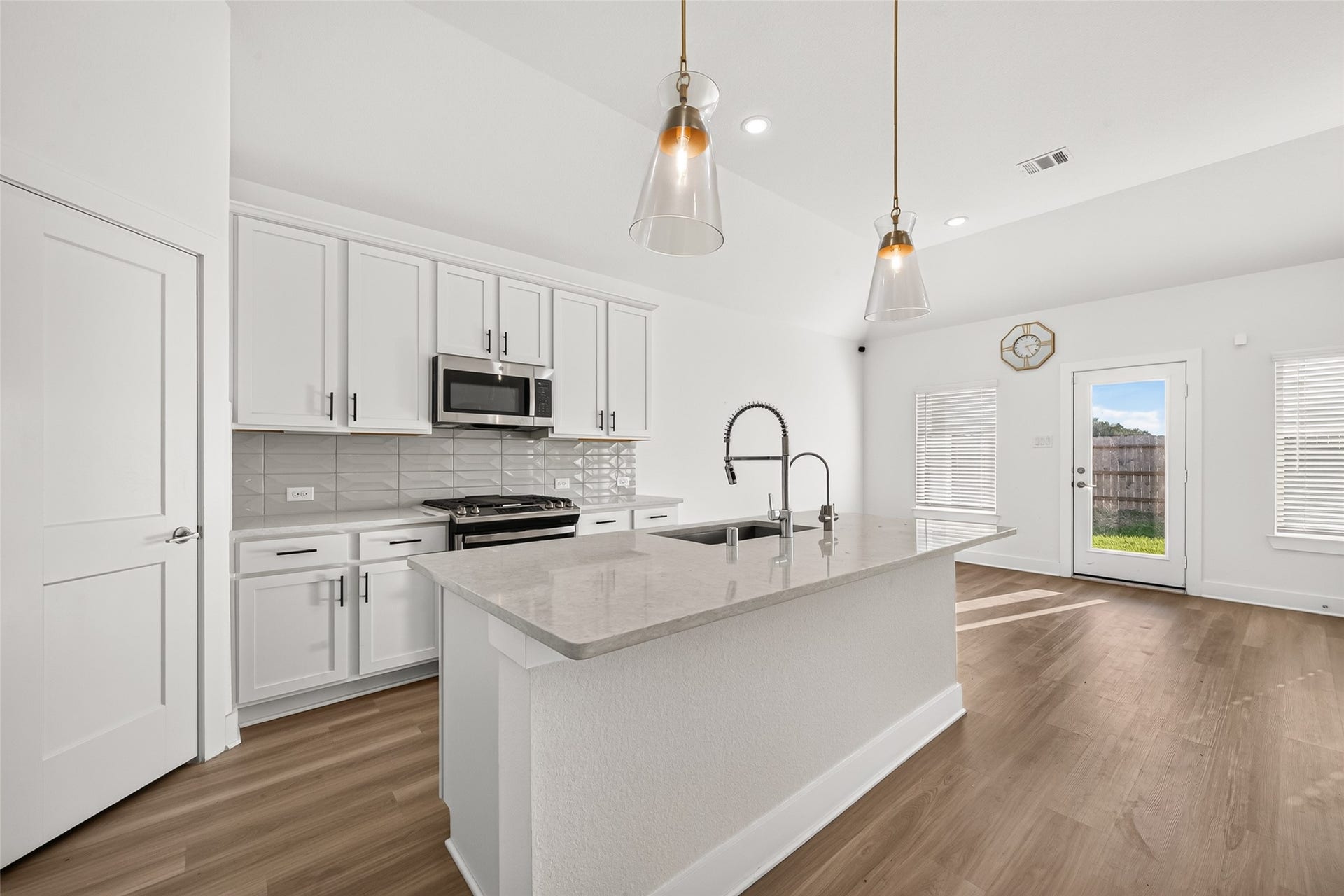 2002 Flatland Drive, Rosenberg, TX 77471 Kitchen island with undermount sink, gooseneck faucet, light countertops, and pendant lighting next to the breakfast area.
