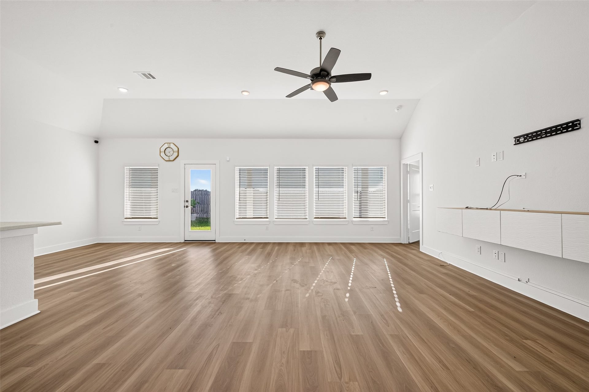 2002 Flatland Drive, Rosenberg, TX 77471 Living room with windows across the back wall, rear door to the yard, ceiling fan, and recessed lighting.