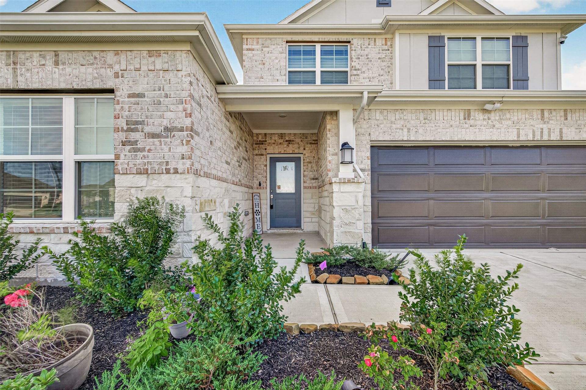2002 Flatland Drive, Rosenberg, TX 77471 Front exterior with brick and stone facade, covered entry, two-car garage, and landscaped beds.