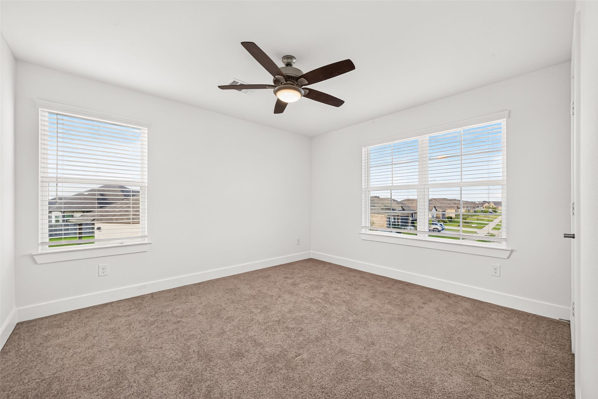 2002 Flatland Drive, Rosenberg, TX 77471 Upstairs bedroom with carpet, ceiling fan, and windows on two walls.
