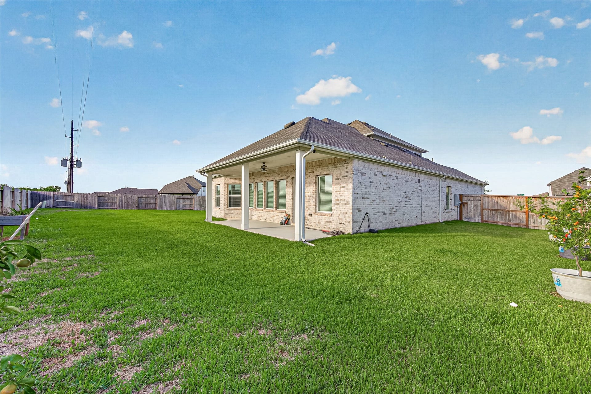 2002 Flatland Drive, Rosenberg, TX 77471 Backyard view showing the covered patio and large grassy yard with wood privacy fence.