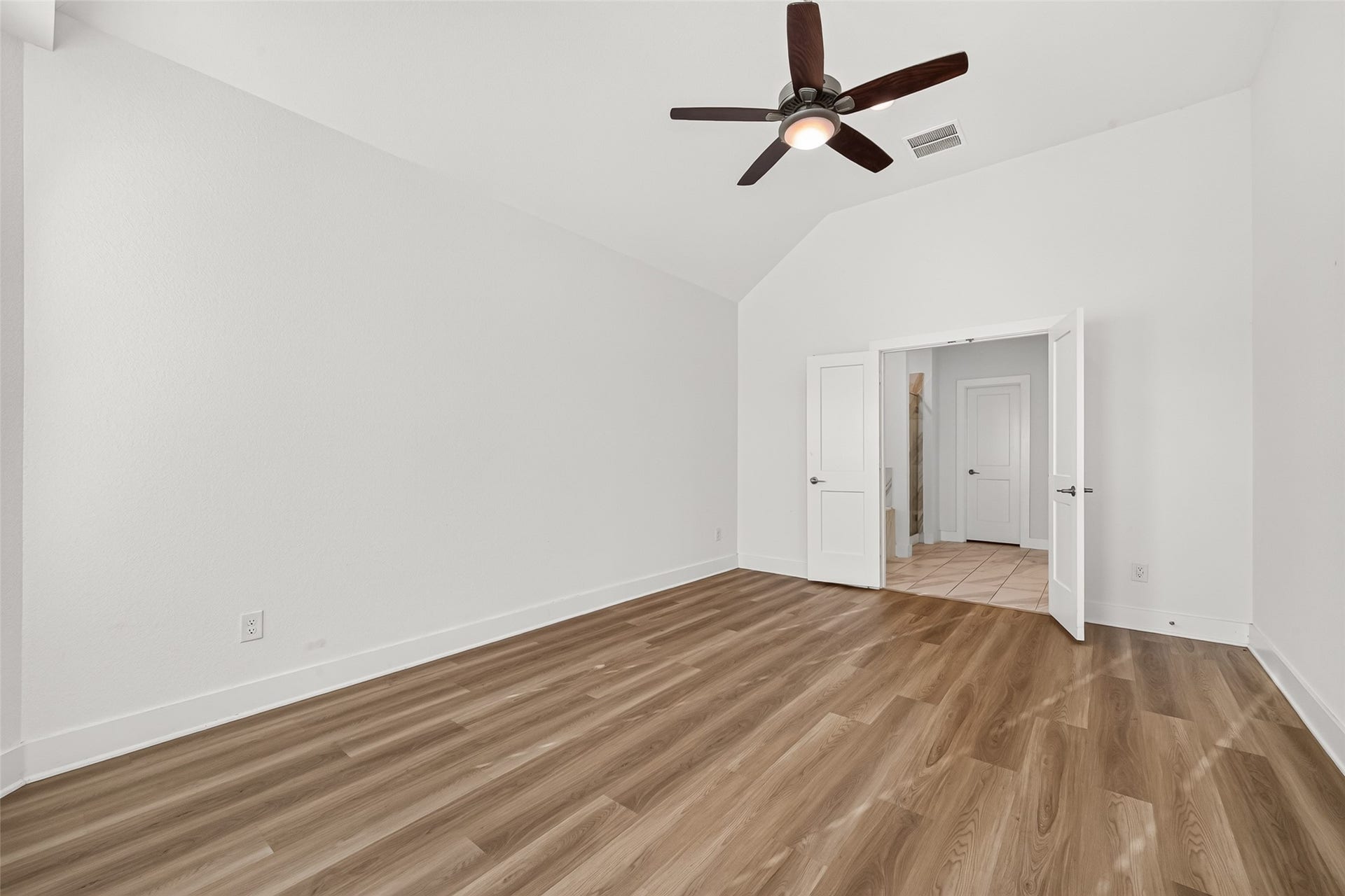 2002 Flatland Drive, Rosenberg, TX 77471 Primary bedroom with vaulted ceiling, ceiling fan, and double-door entry.