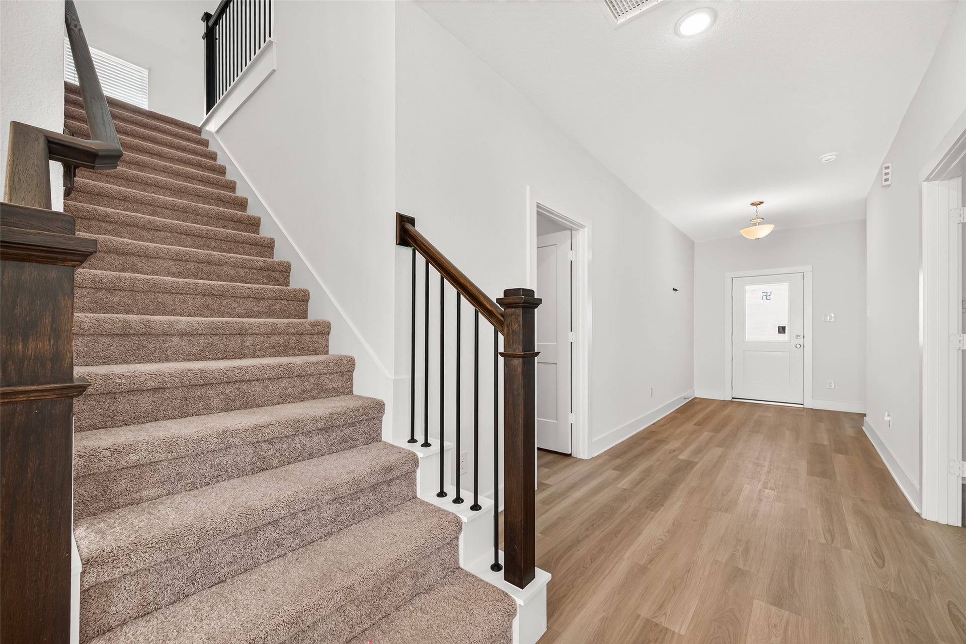 2002 Flatland Drive, Rosenberg, TX 77471 Staircase with carpeted treads, wood handrail, and wrought iron balusters, open to the hallway.