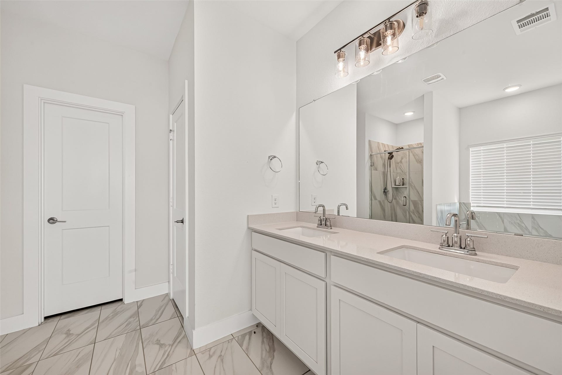 2002 Flatland Drive, Rosenberg, TX 77471 Primary bathroom double vanity with two sinks, large mirror, and vanity lighting.