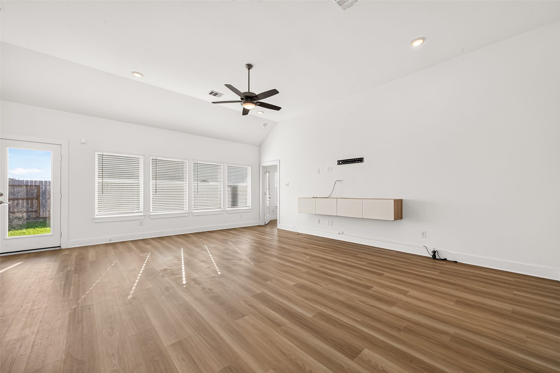 2002 Flatland Drive, Rosenberg, TX 77471 Living room with high ceiling, ceiling fan, recessed lighting, and a wall of windows with door access to the backyard.