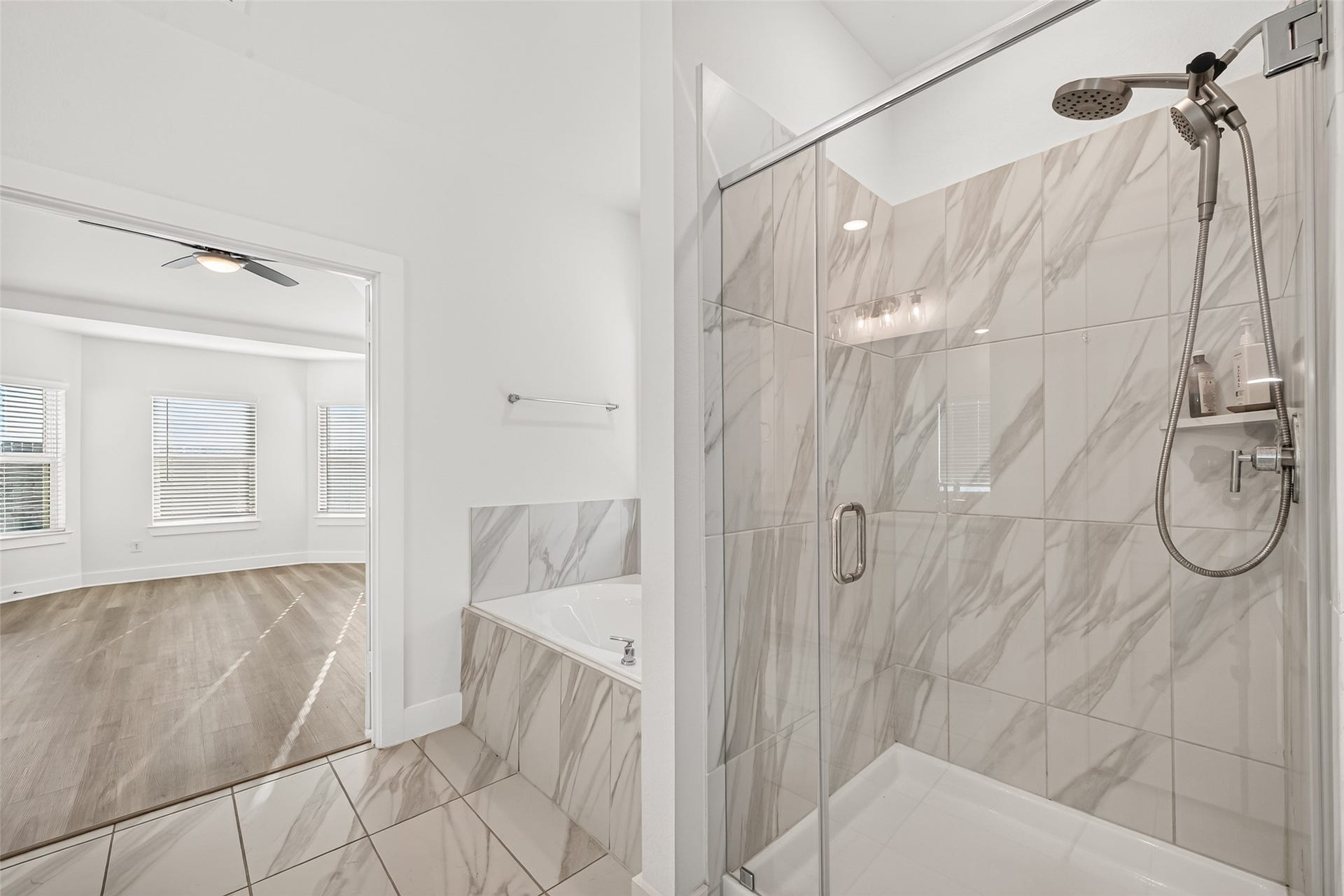 2002 Flatland Drive, Rosenberg, TX 77471 Walk-in shower with frameless glass enclosure, handheld showerhead, and marble-look tile.