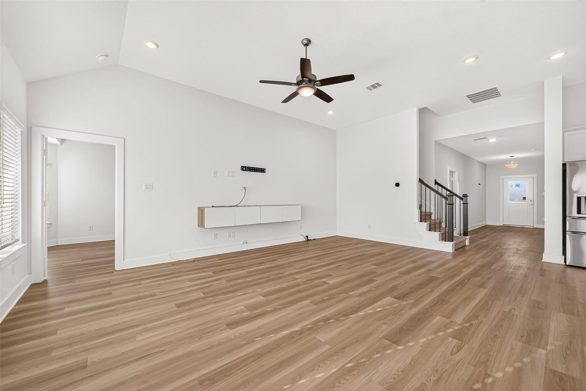 2002 Flatland Drive, Rosenberg, TX 77471 Living room with vaulted ceiling and ceiling fan, open to the hallway, staircase, and kitchen.