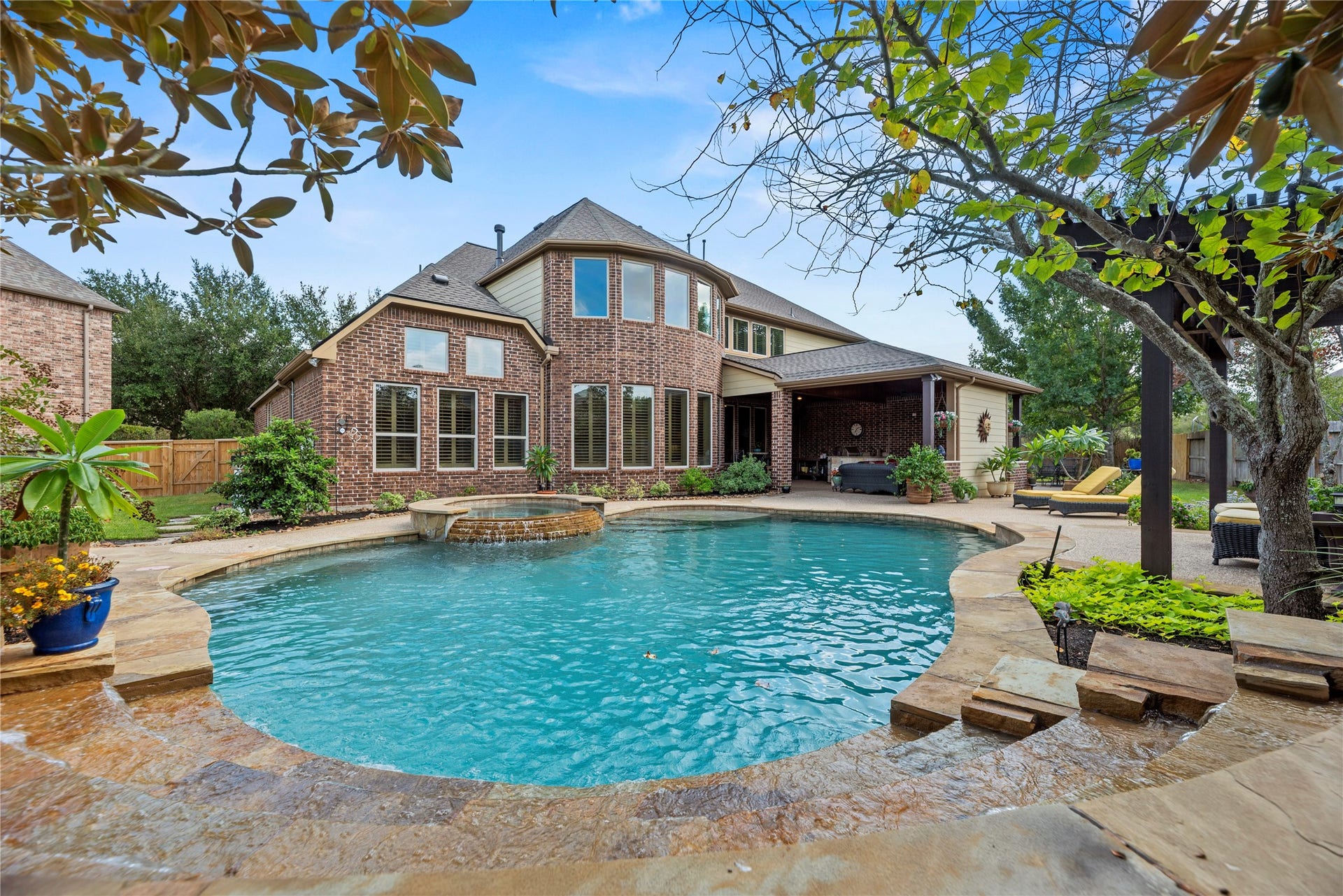 12002 Tall Haven Lane, Cypress, TX 77433 Stunning view of the swimming pool with the home's beautiful brick exterior in the background.