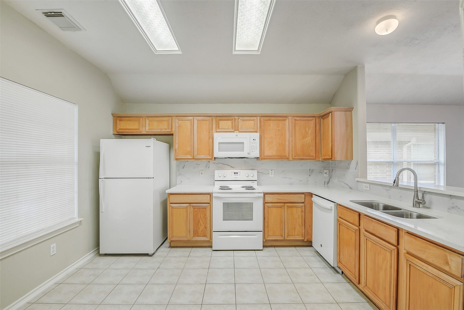 12115 Lucky Meadow Dr, Tomball, TX 77375 Spacious kitchen featuring beautiful quartz countertops, with updated microwave and dishwasher, offering a fresh, modern space for cooking and entertaining.