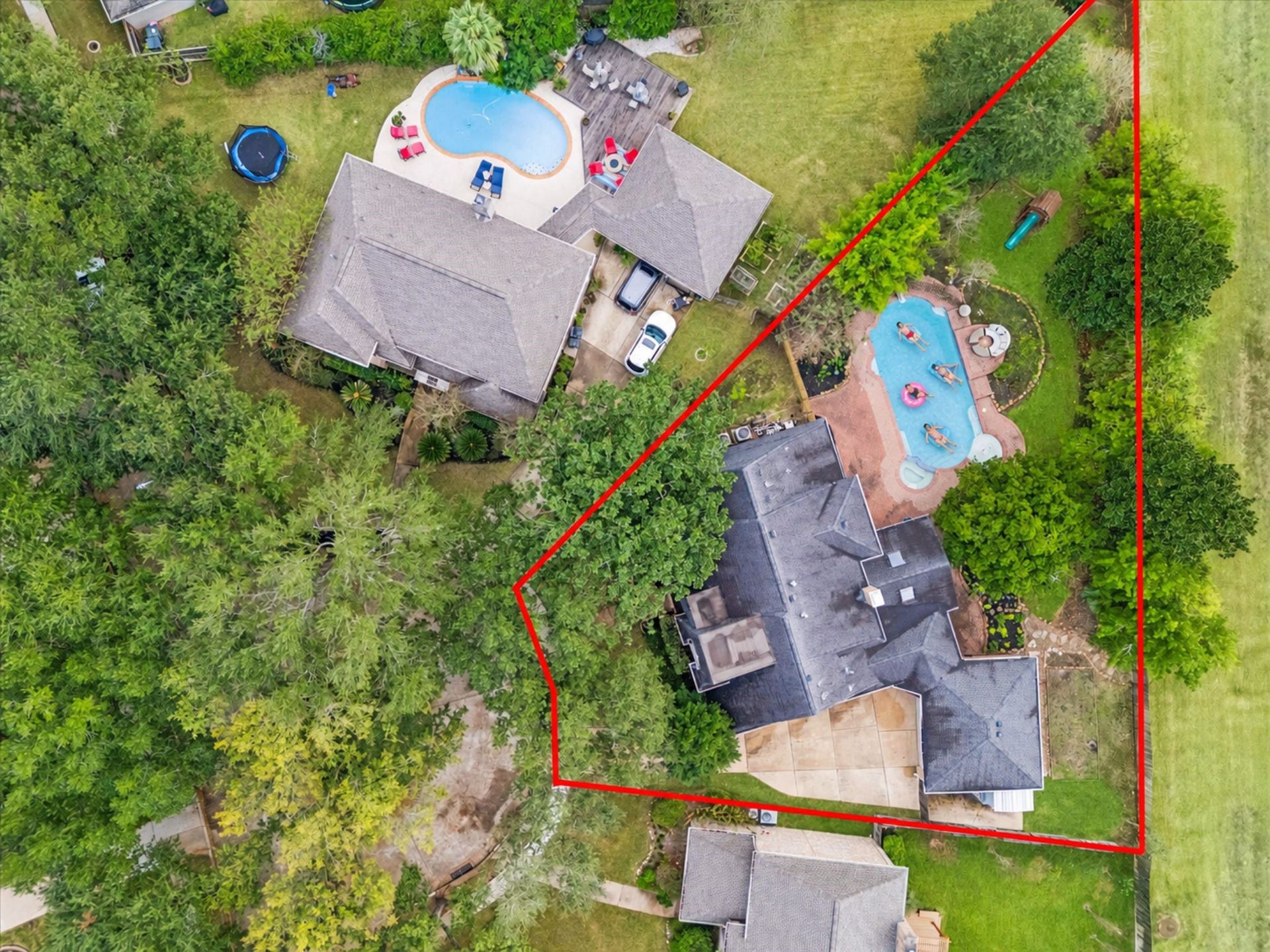This aerial highlights the home's impressively deep, tree-canopied lot, showcasing the main residence and its sprawling, fenced outdoor entertainment area with a large in-ground pool.