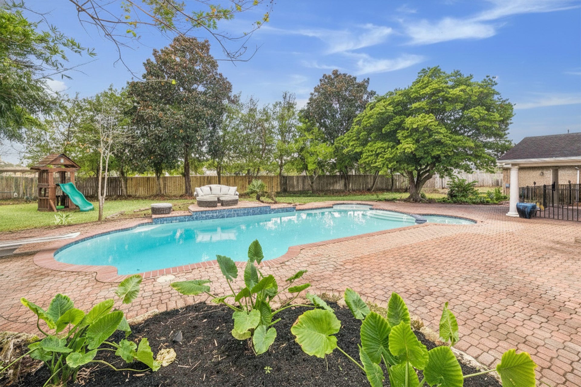 The expansive backyard features stunning brick paving that surrounds the pool and spa area, providing a durable surface perfect for sunbathing and outdoor gatherings.