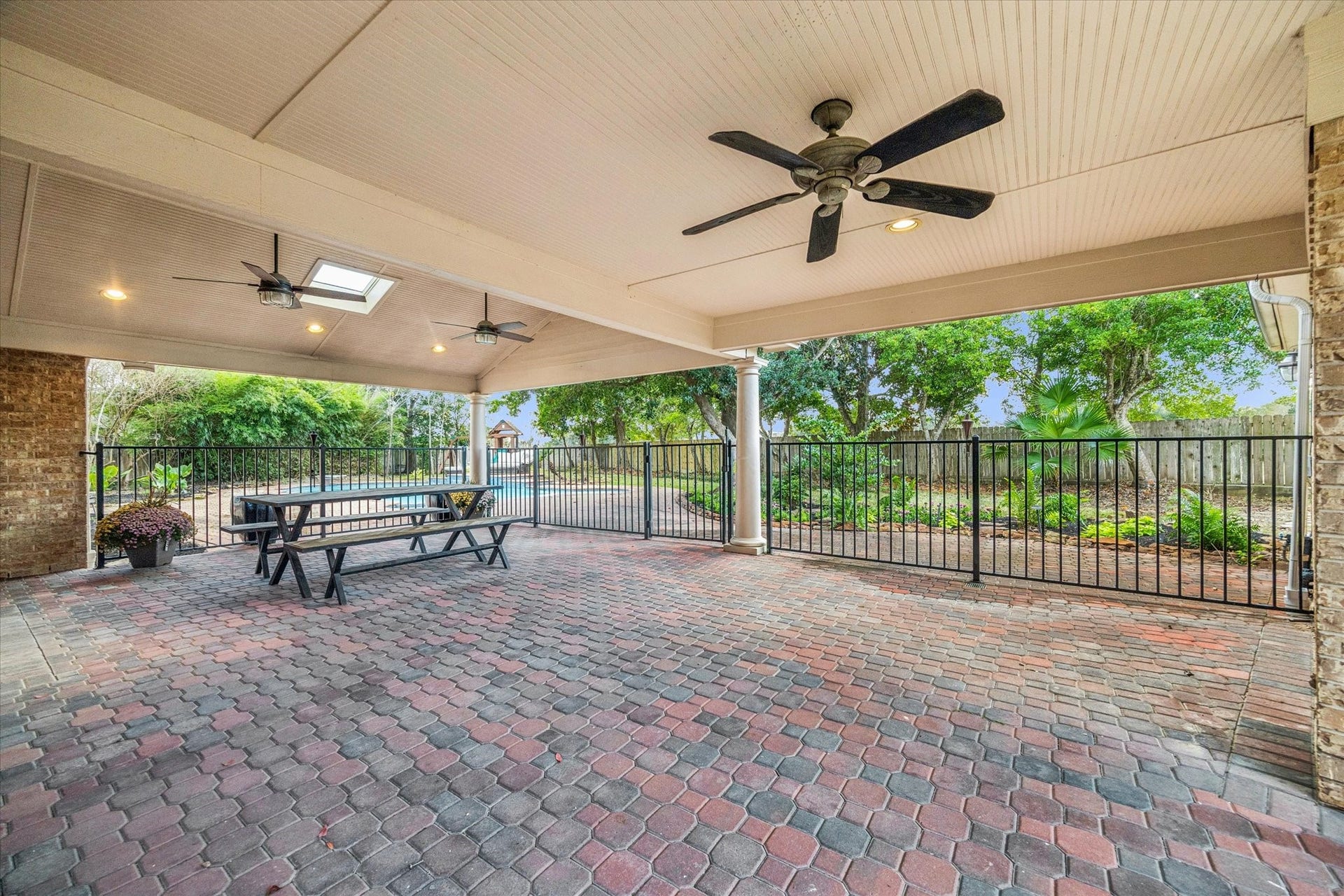 A view of the large covered patio, which features a new child-proof fence and ceiling fans, leading out to the spacious backyard.