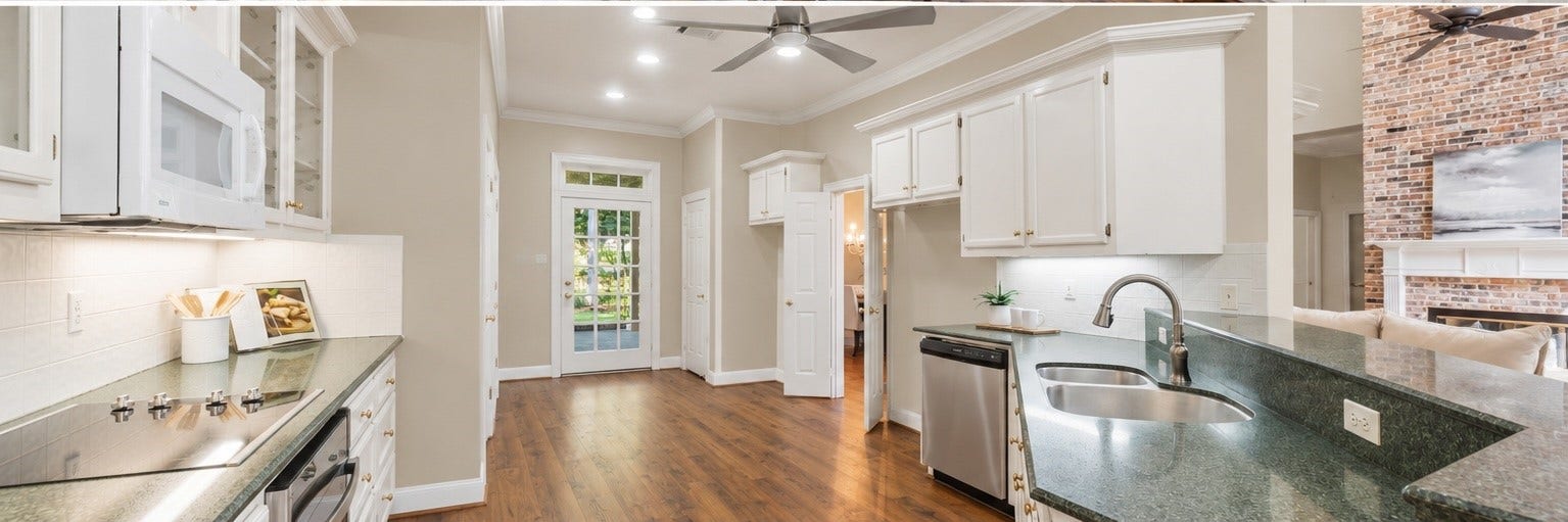 AI-generated visualization showing the kitchen with the existing wallpaper removed and replaced with neutral paint. Provided to illustrate the potential impact of a simple cosmetic update; actual property currently has wallpaper.