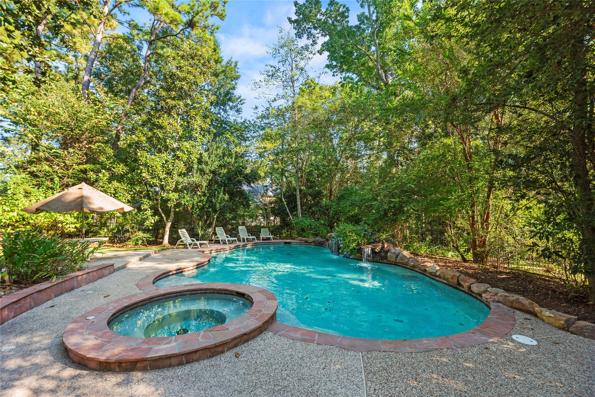 Tucked among mature trees, the pool and spa create a peaceful backyard retreat with rock waterfalls, shaded lounging areas, and a wonderfully private setting.