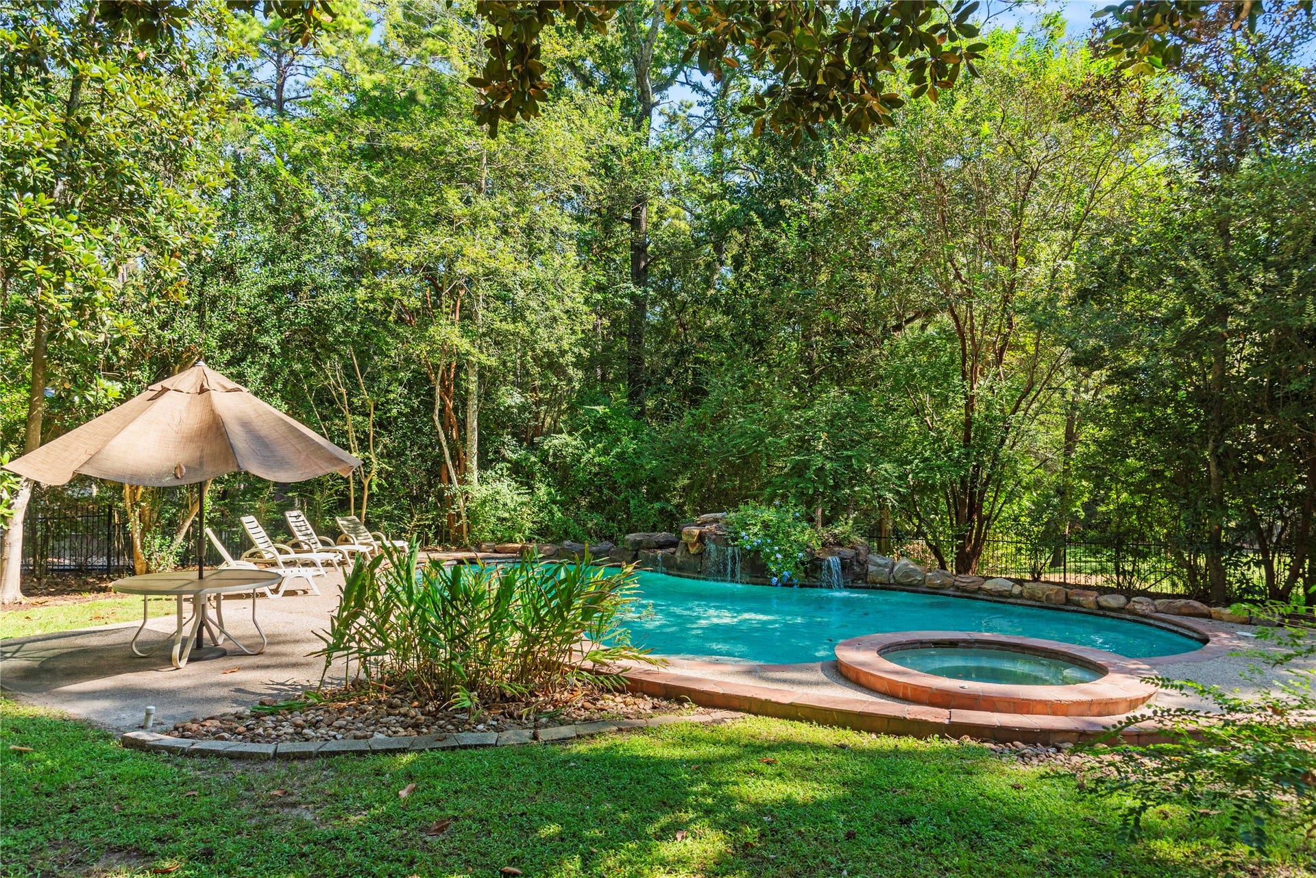 Resort-like pool and spa tucked beneath a canopy of mature trees, complete with rock waterfalls and generous space for lounging and entertaining.