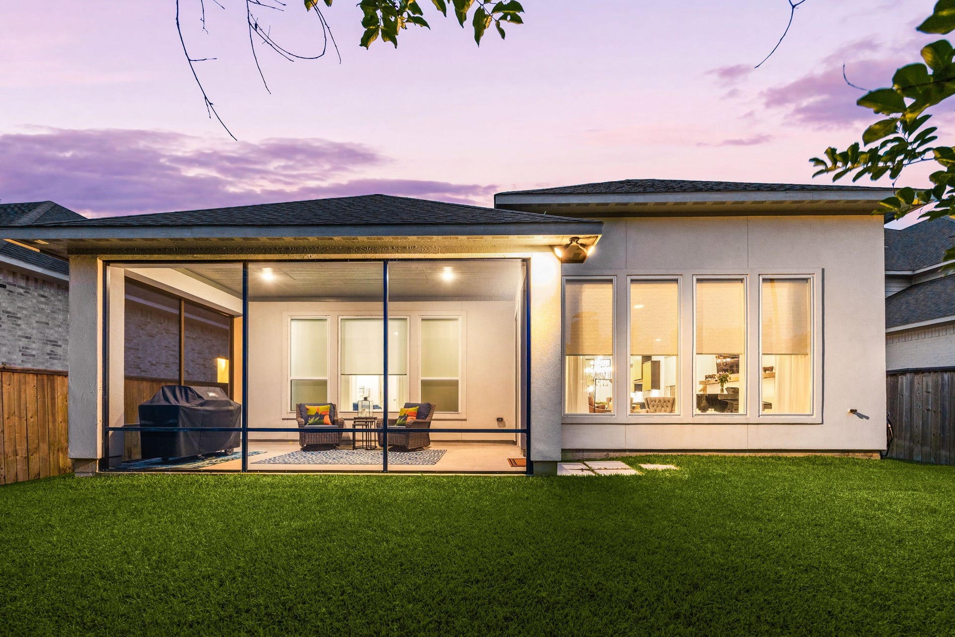 18 Gentle Branch Place, The Woodlands, TX 77375 A stunning view of modern architecture at twilight. The expansive windows and motorized screened-in patio showcase the seamless indoor-outdoor flow of this home. The level, manicured lawn and private fencing provide a tranquil backdrop for this exceptional Creekside Park residence.