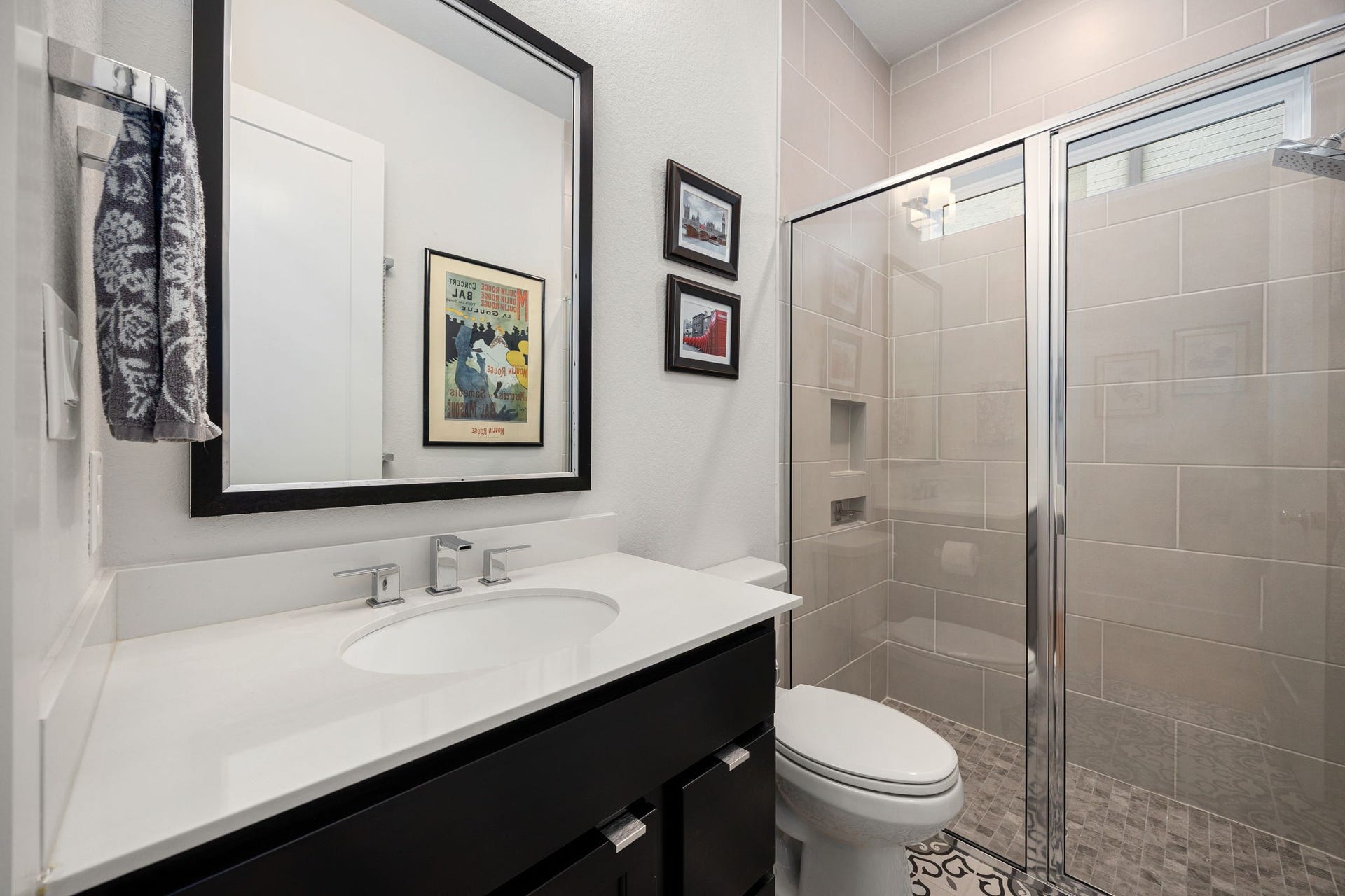 18 Gentle Branch Place, The Woodlands, TX 77375 This stylish secondary bathroom features a sleek dark vanity with a crisp stone countertop and a spacious glass-enclosed walk-in shower. The modern tile work and contemporary fixtures provide a polished, high-end feel for guests and family alike.