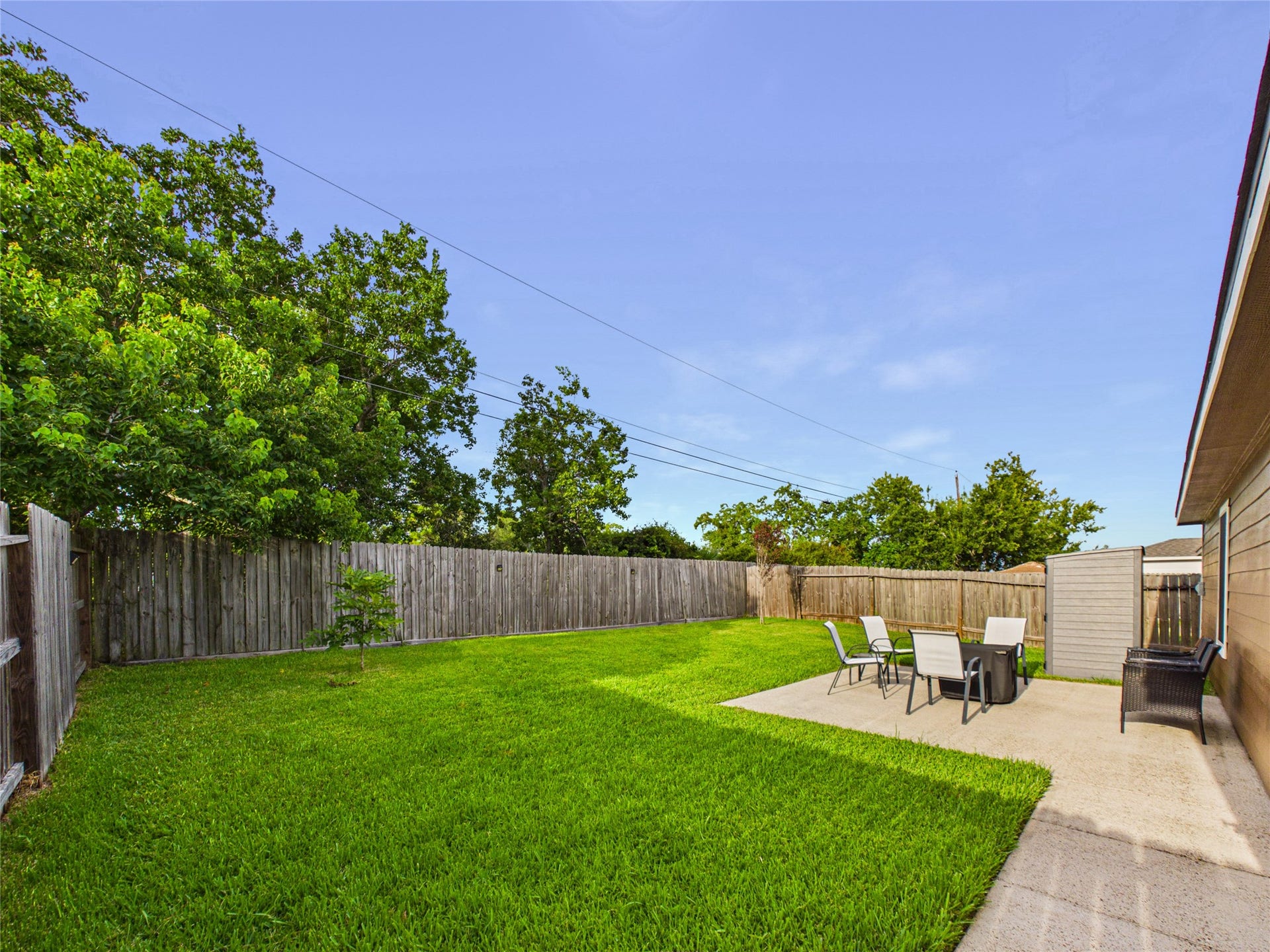 9022 Barracuda Drive, Texas City, TX 77591 Spacious backyard with lush green lawn, a cozy patio area for outdoor dining, and a privacy fence, perfect for relaxation and entertainment.