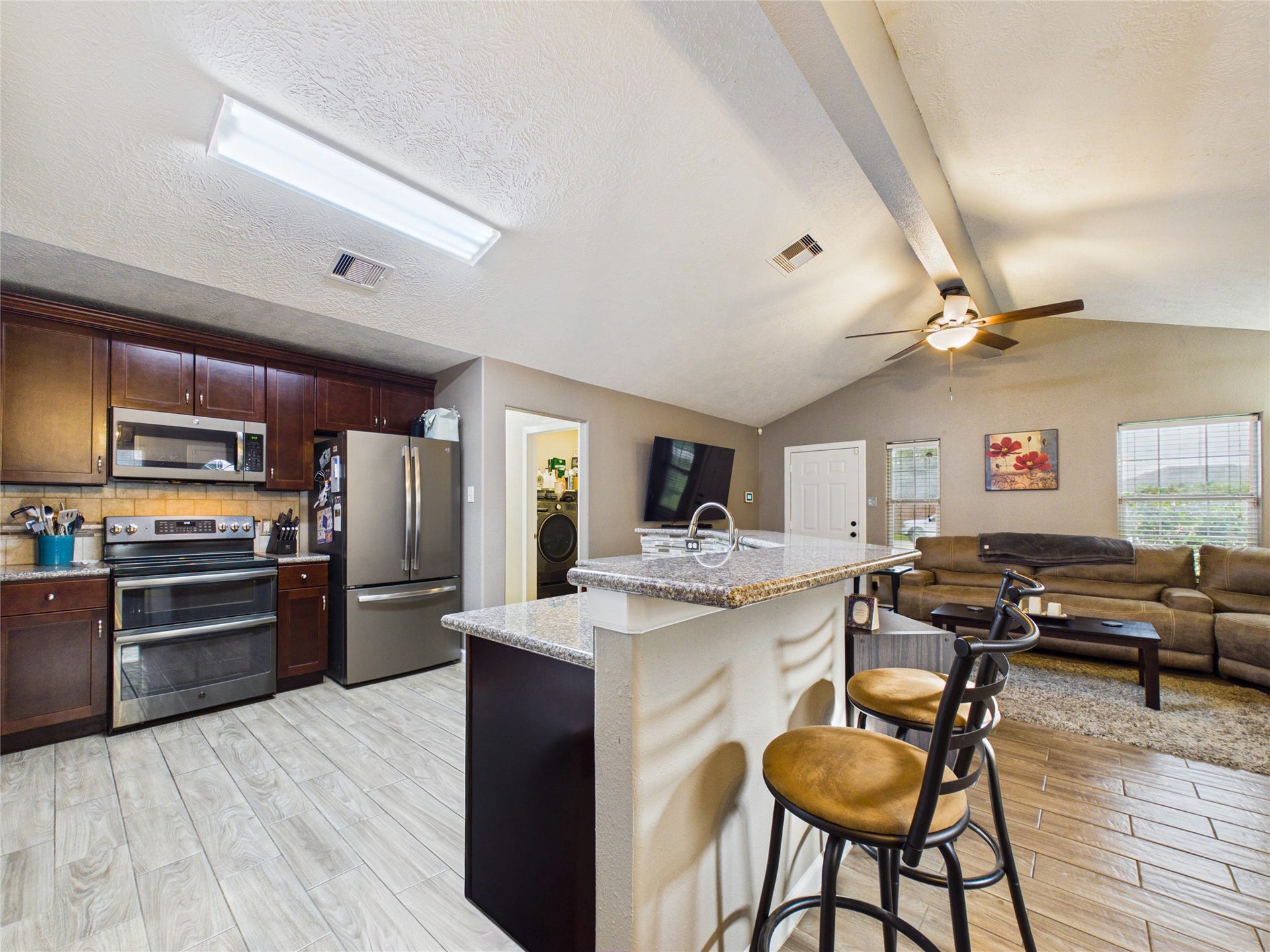 9022 Barracuda Drive, Texas City, TX 77591 The kitchen features stainless steel appliances, dark wood cabinetry, and a breakfast bar overlooking the living.