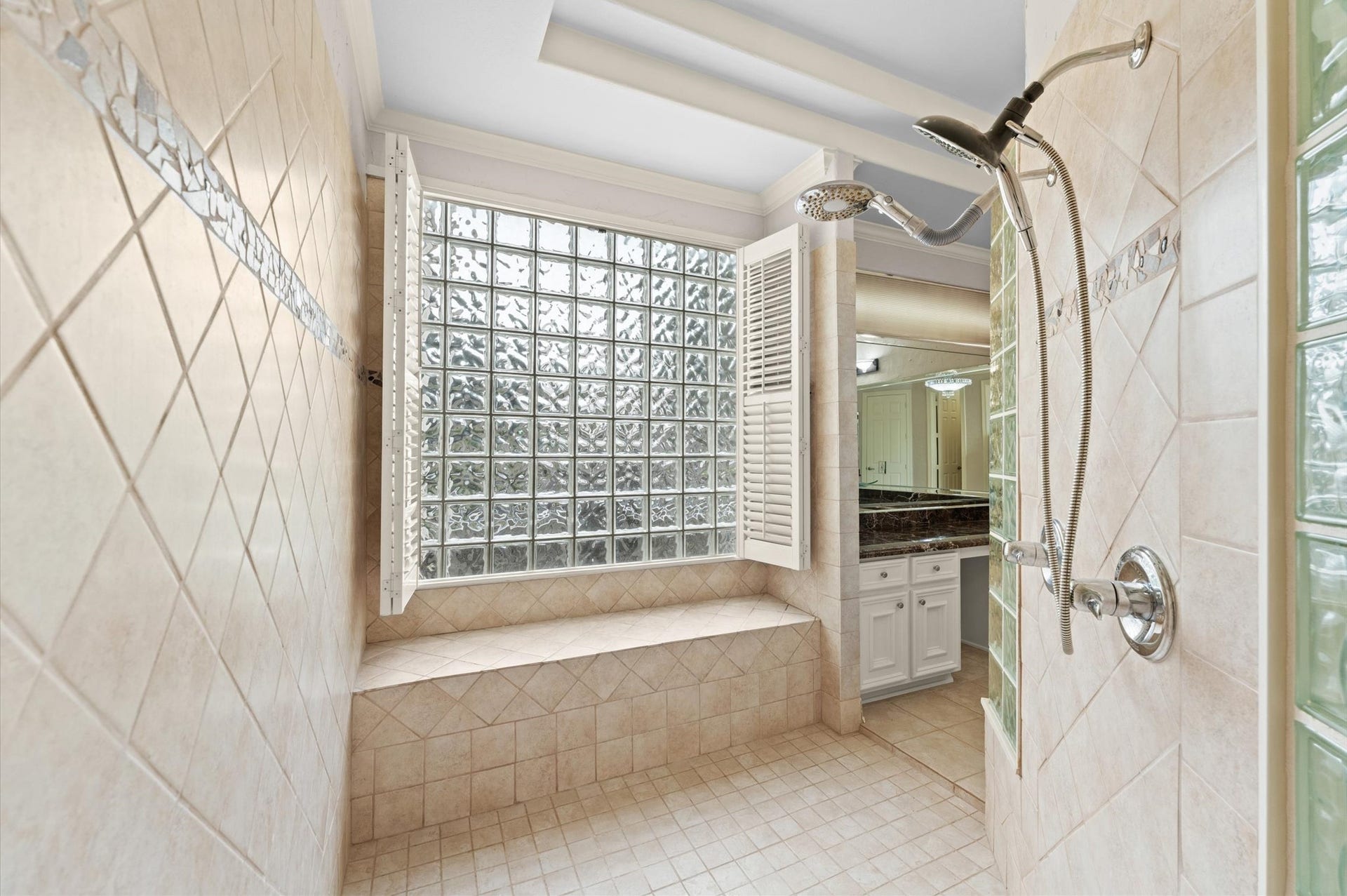 1830 Forest Gate Circle, Sugar Land, TX 77479 A view of the walk-through shower has multiple shower heads and large glass block window with shower bench.
