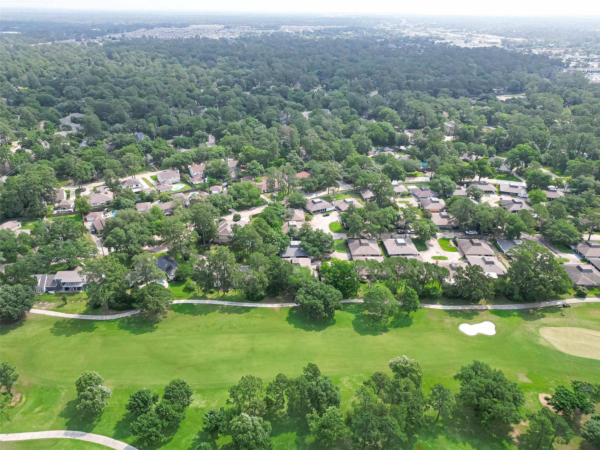 20 Champions Colony E, Houston, TX 77069 Behold the panoramic vista of the Legendary Champion Forest area from above, where lush greens harmonize with the elegant rooftops of homes nestled within this picturesque neighborhood.