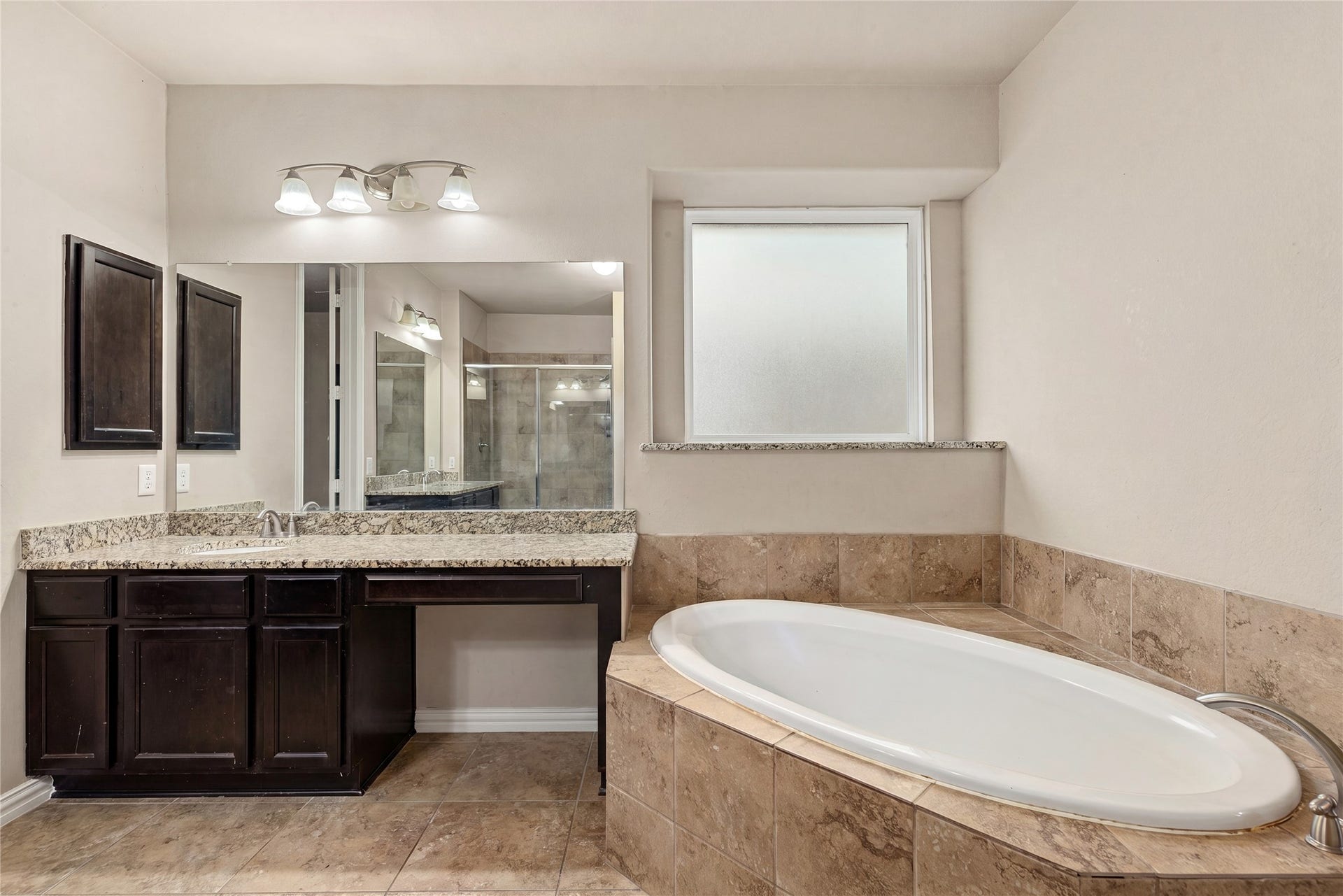 7018 Pearl Terrace Lane, Richmond, TX 77469 Relaxing primary bath with a soaking garden tub, granite vanity with seated makeup space, and a separate walk-in shower.