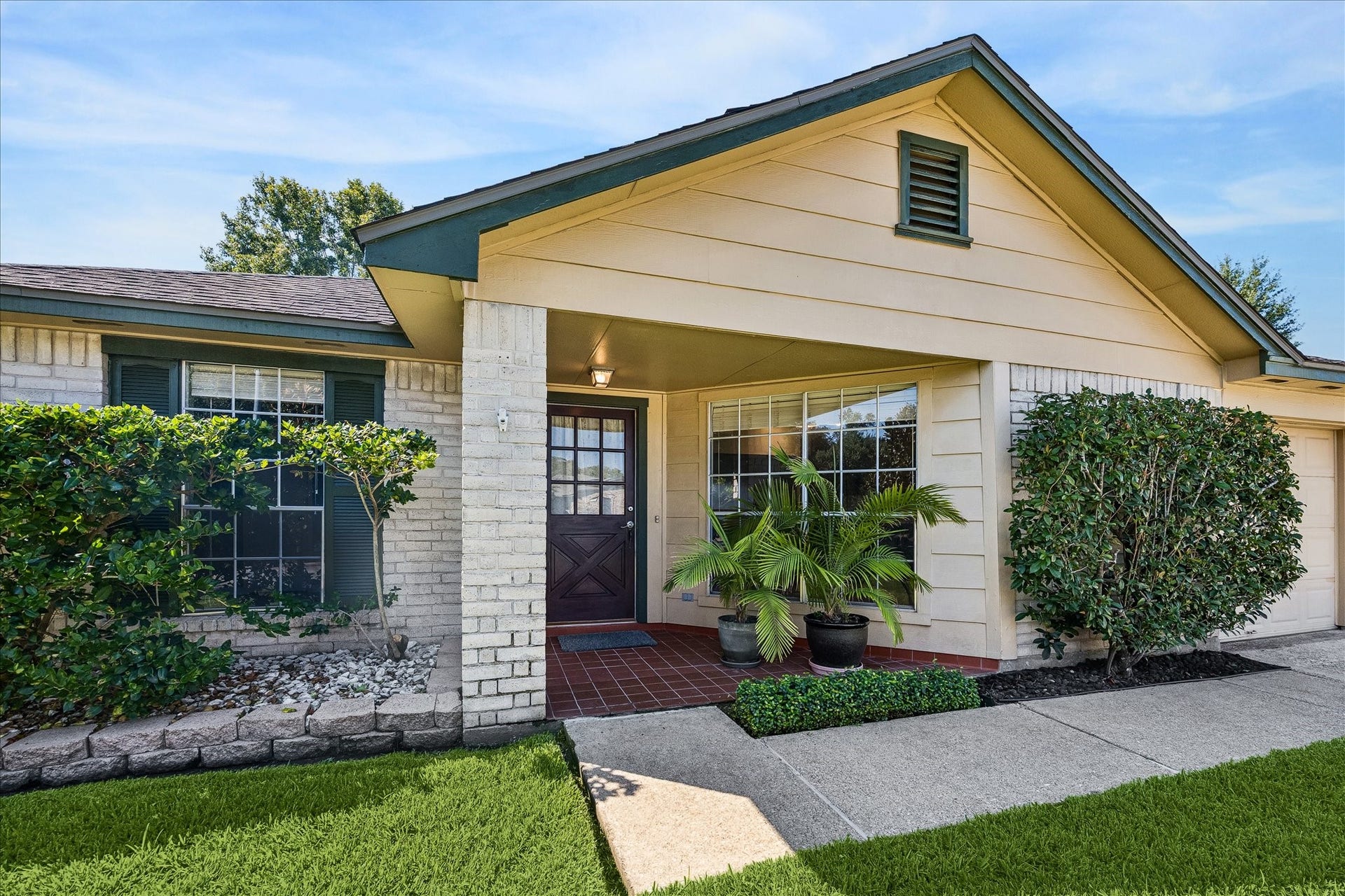 16911 Summer Dawn Place, Houston, TX 77095 Covered front entry pairs brick and siding with established landscaping, creating a welcoming approach to the home.