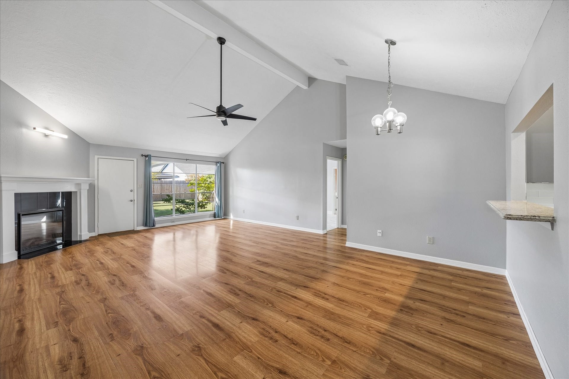 16911 Summer Dawn Place, Houston, TX 77095 Wide-angle view highlights the open relationship between the living and dining areas beneath the high ceiling and exposed beam, with clear sightlines toward the backyard.