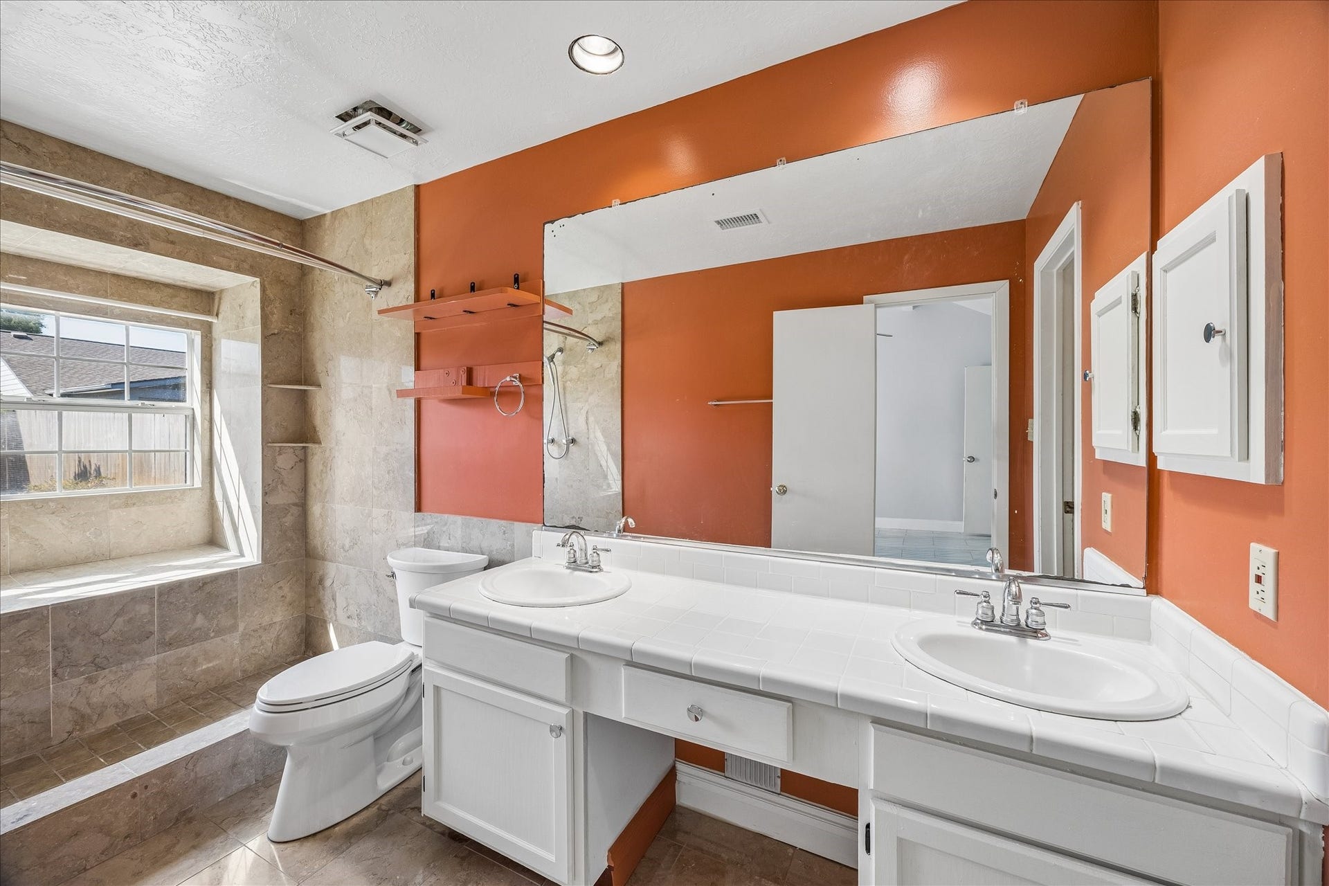 16911 Summer Dawn Place, Houston, TX 77095 Primary bath offers a long dual-sink vanity, broad mirror, tiled finishes, and a warm accent wall that adds character to the space.